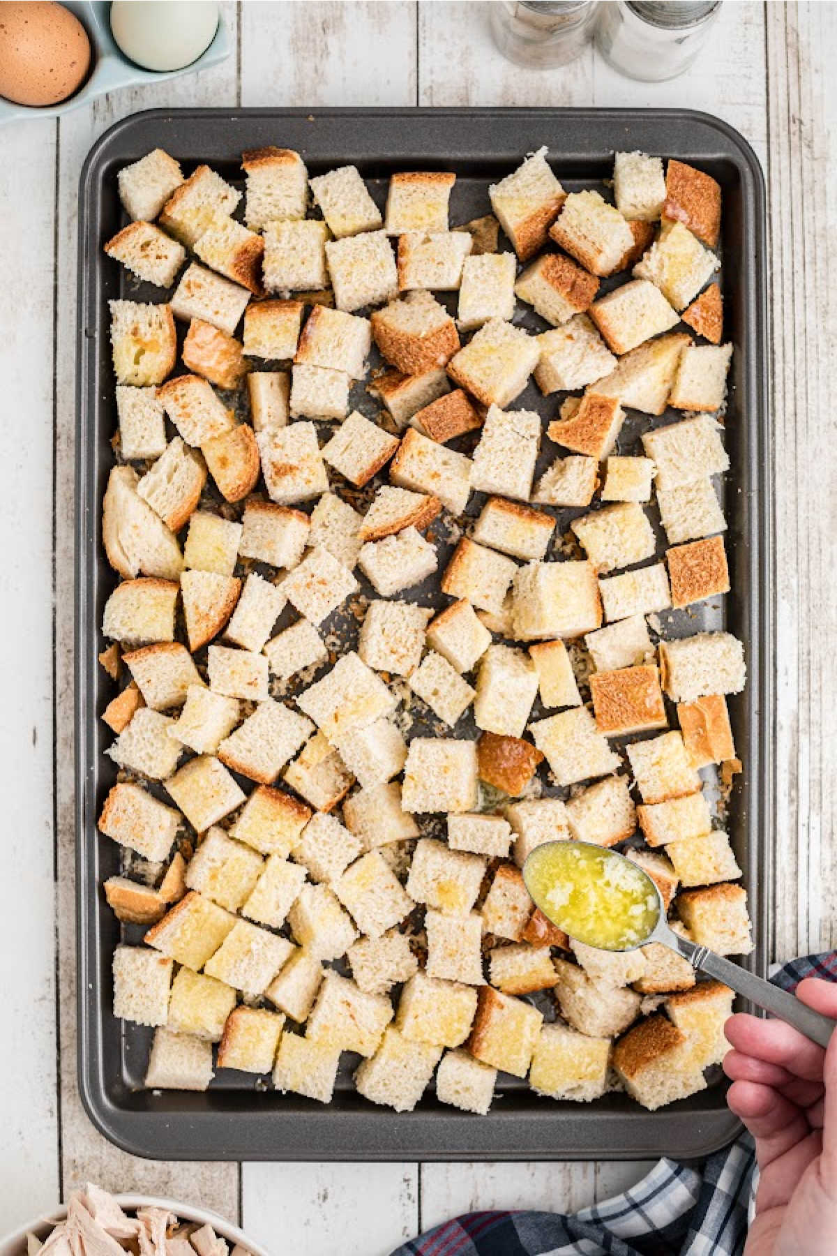Melted butter being drizzled on bread cubes.