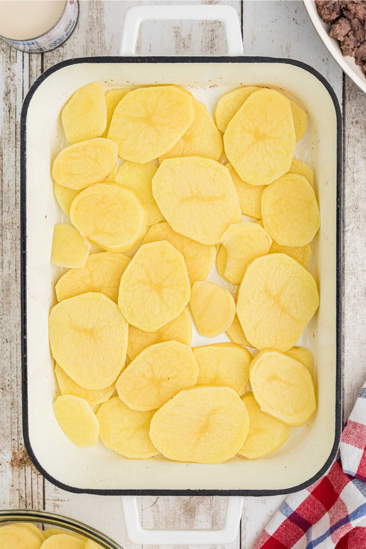 Sliced potatoes laid out in a large casserole dish.