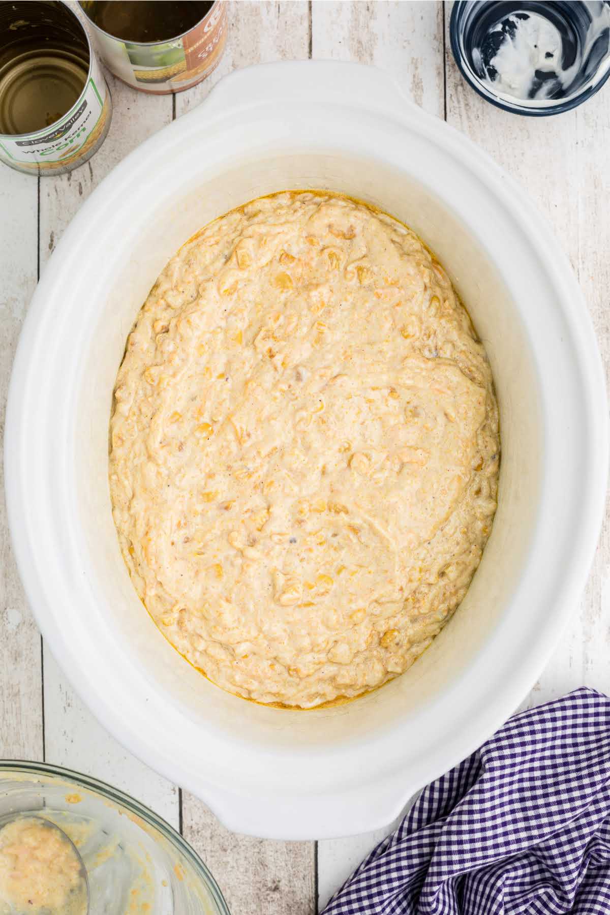 Corn casserole ingredients added to a large crock pot.