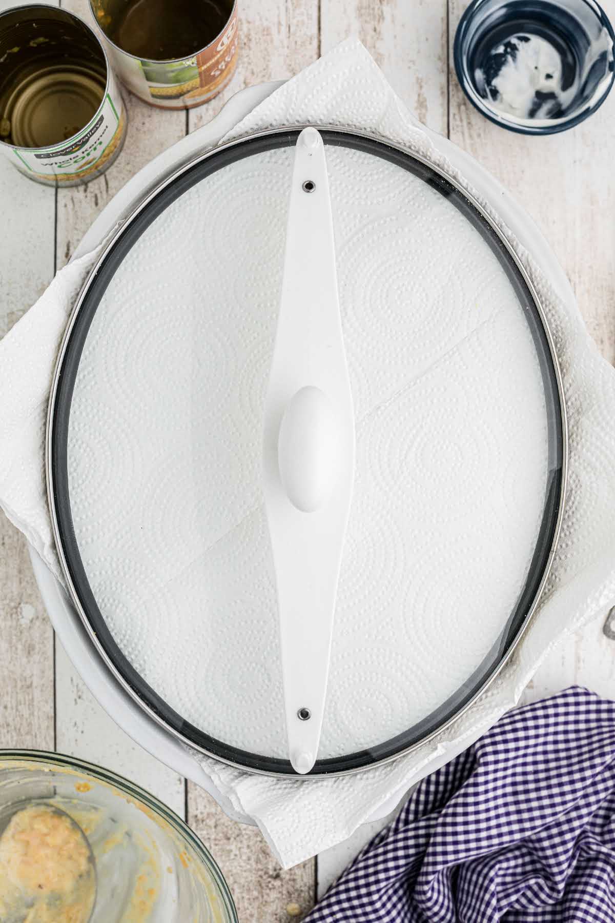 A crock pot with paper towel under the lid.