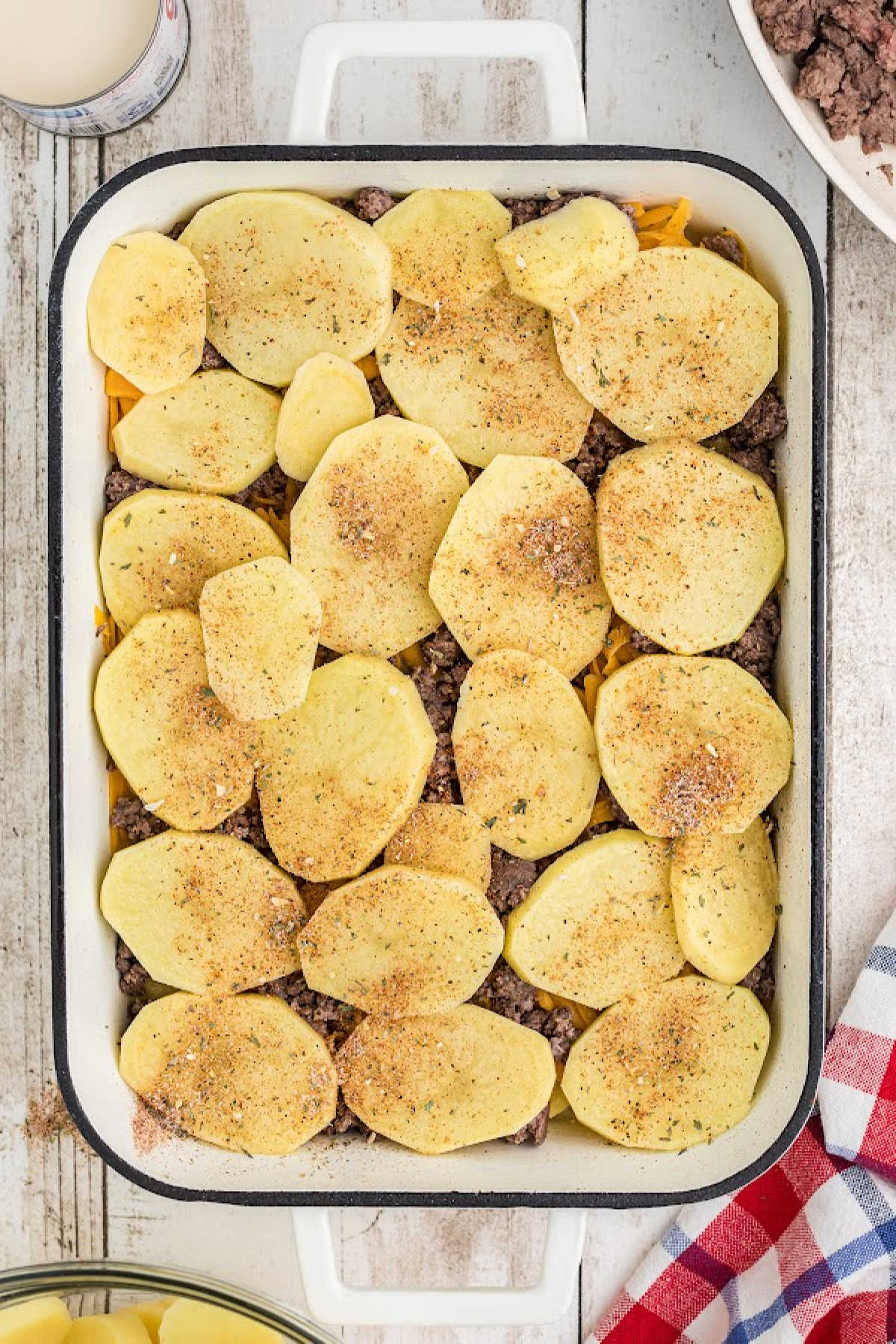 Potato slices on top of other ingredients in a baking dish.