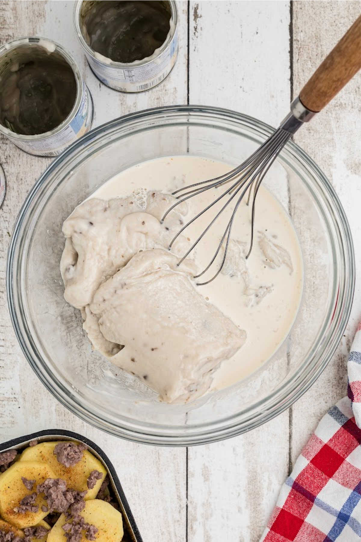 A large mixing bowl with a whisk and soup and other ingredients.