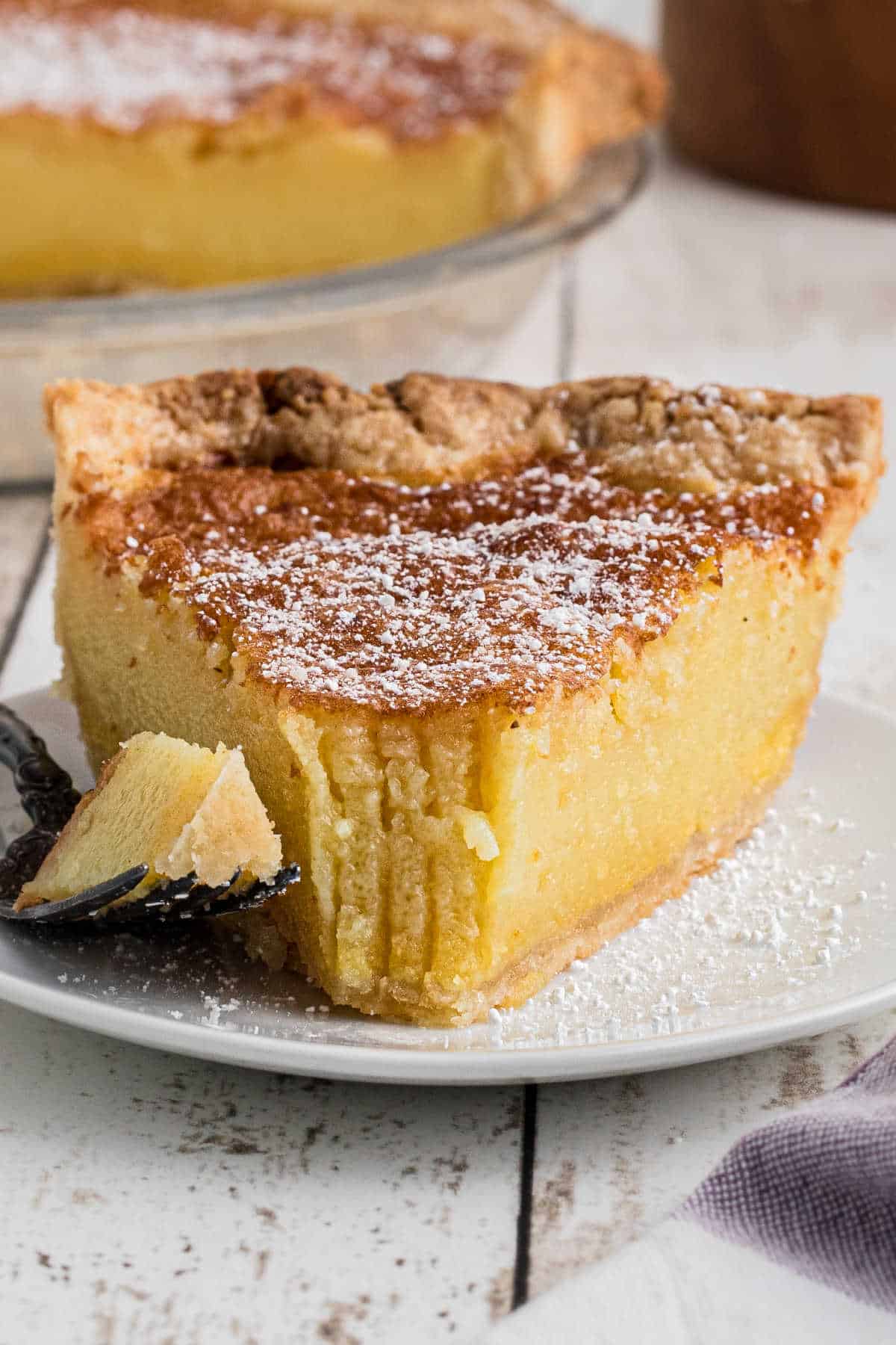 A slice of old fashioned chess pie with a fork taking a bite.