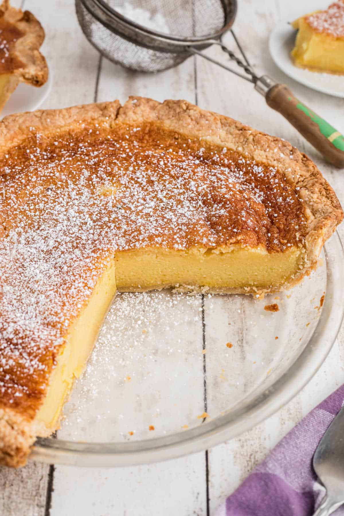 An old fashioned chess pie with some slices missing.