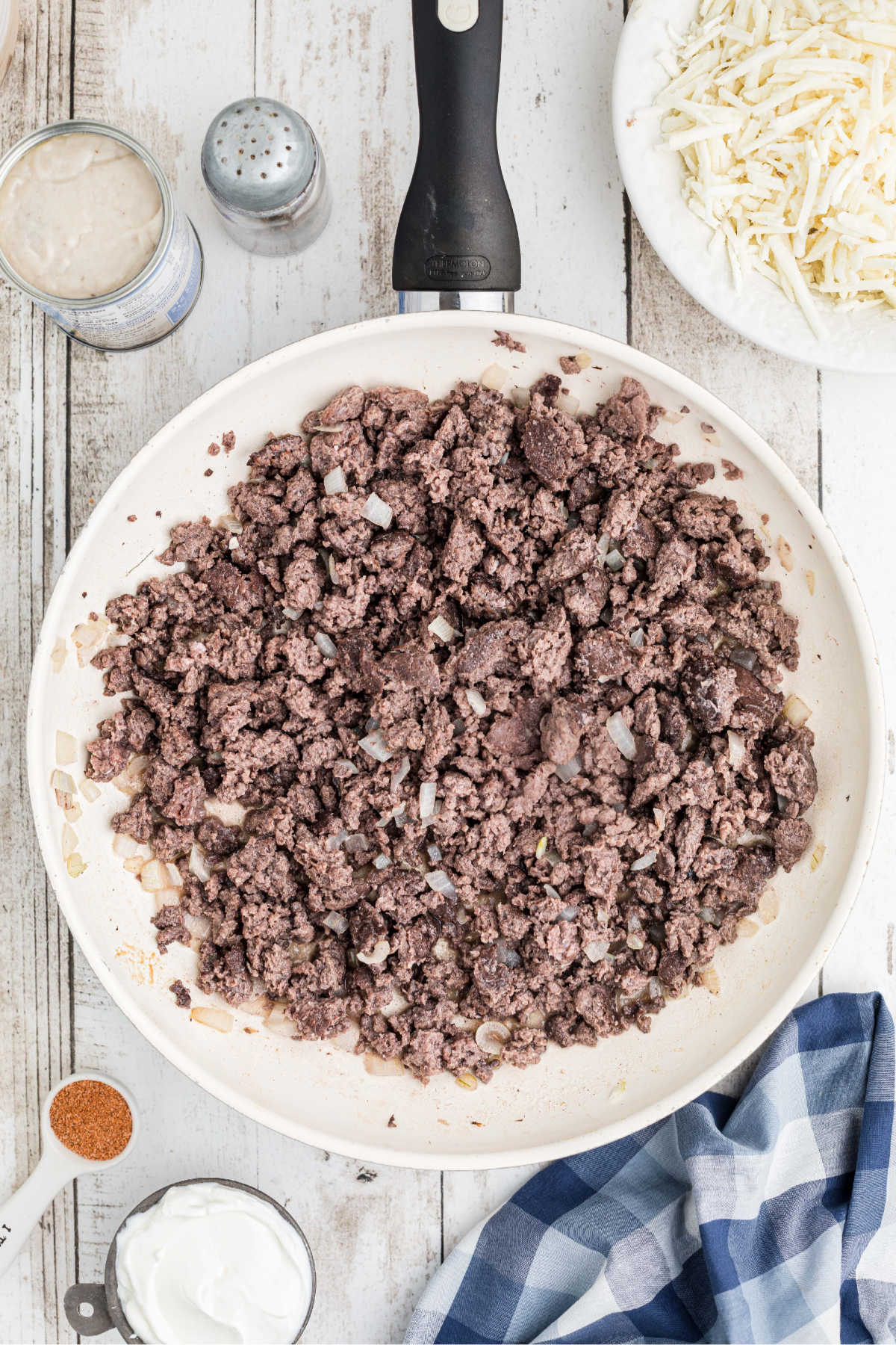 A large skillet with ground beef being cooked.