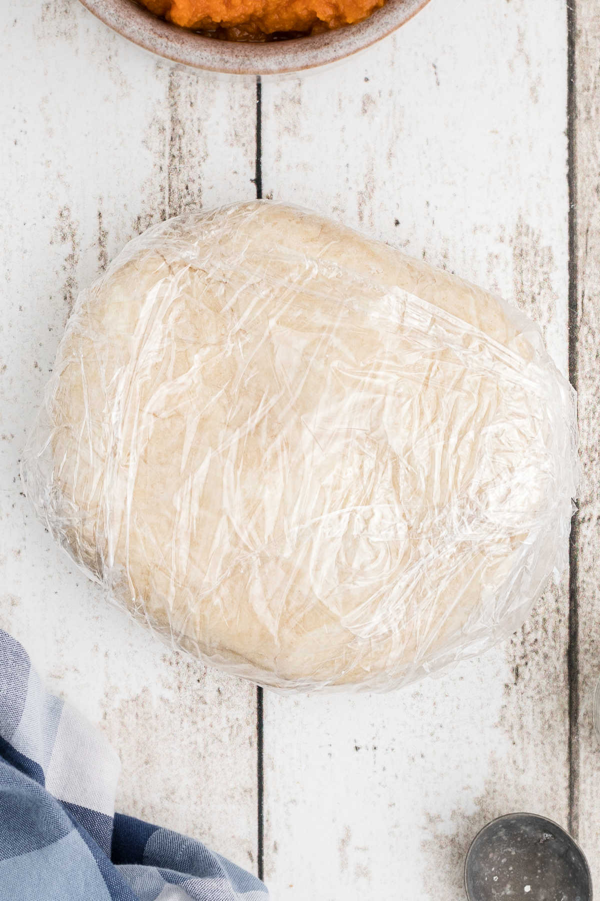 A disc of dough wrapped in plastic wrap.