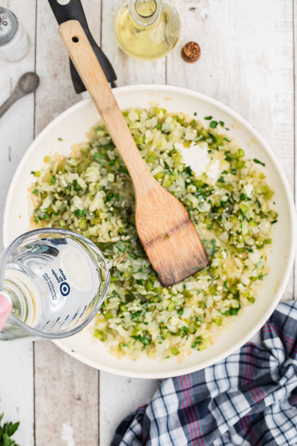 Water being poured into a skillet of cooked vegetables.