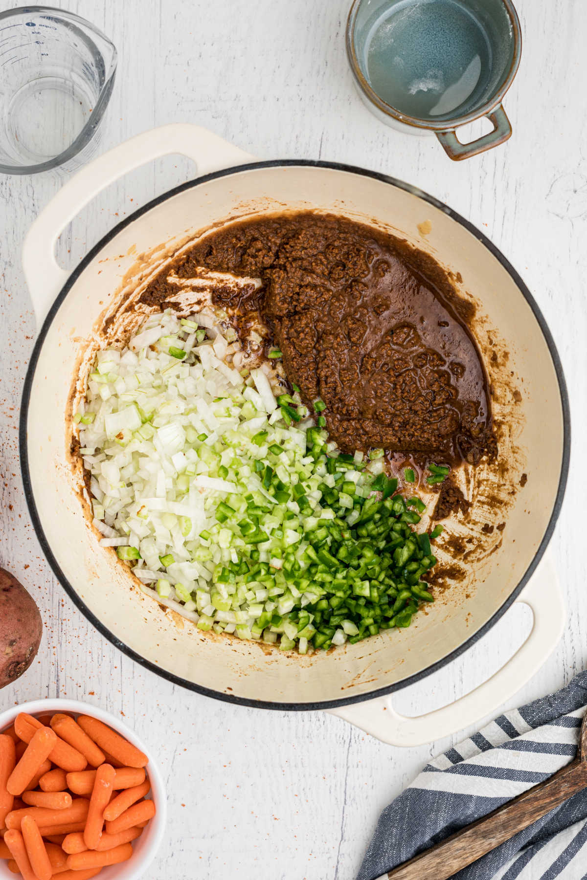 Diced onions and peppers added to a pot with a dark roux.
