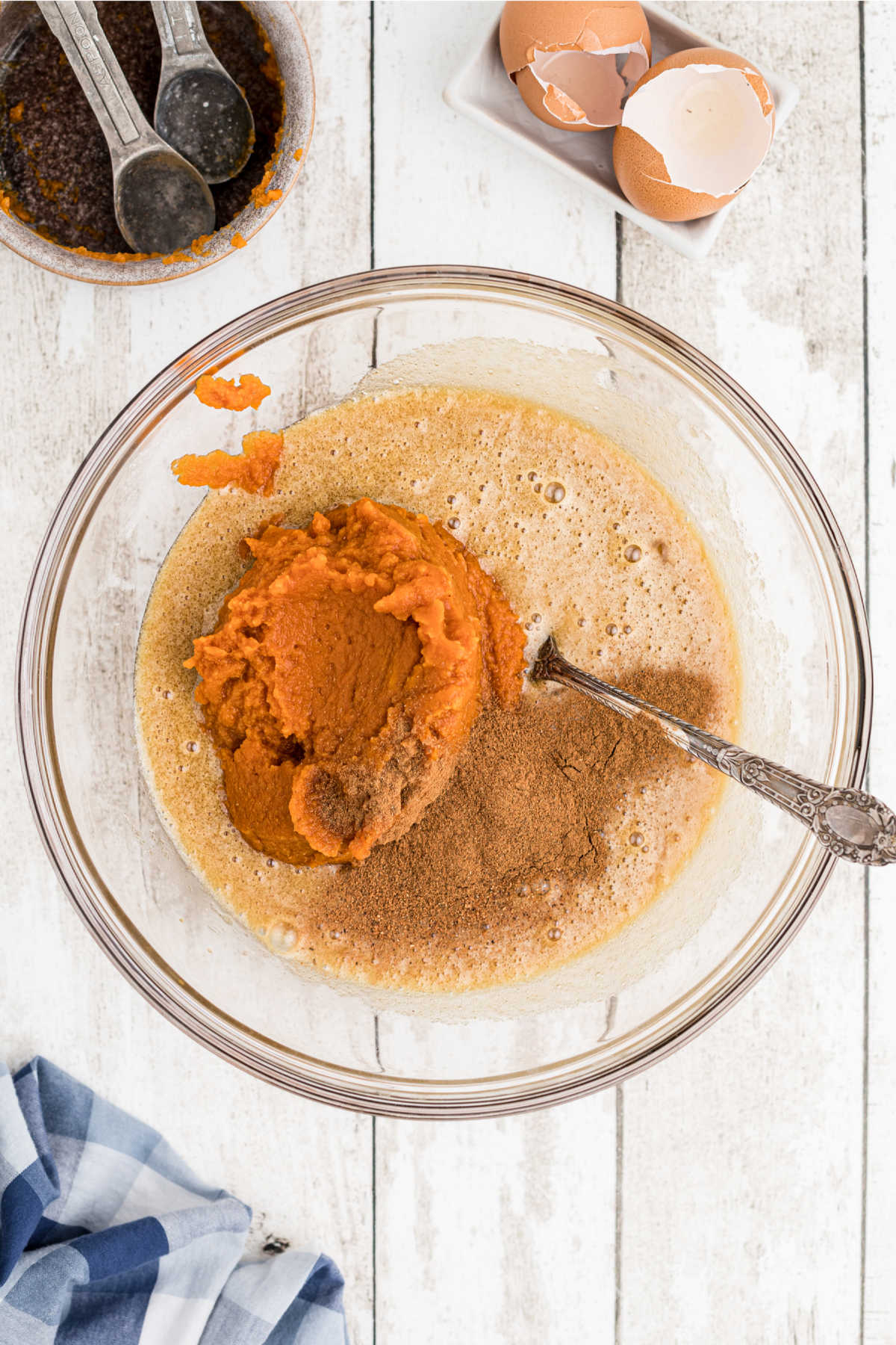 Pumpkin, milk and cream with spices being added to a flour sugar mixture.