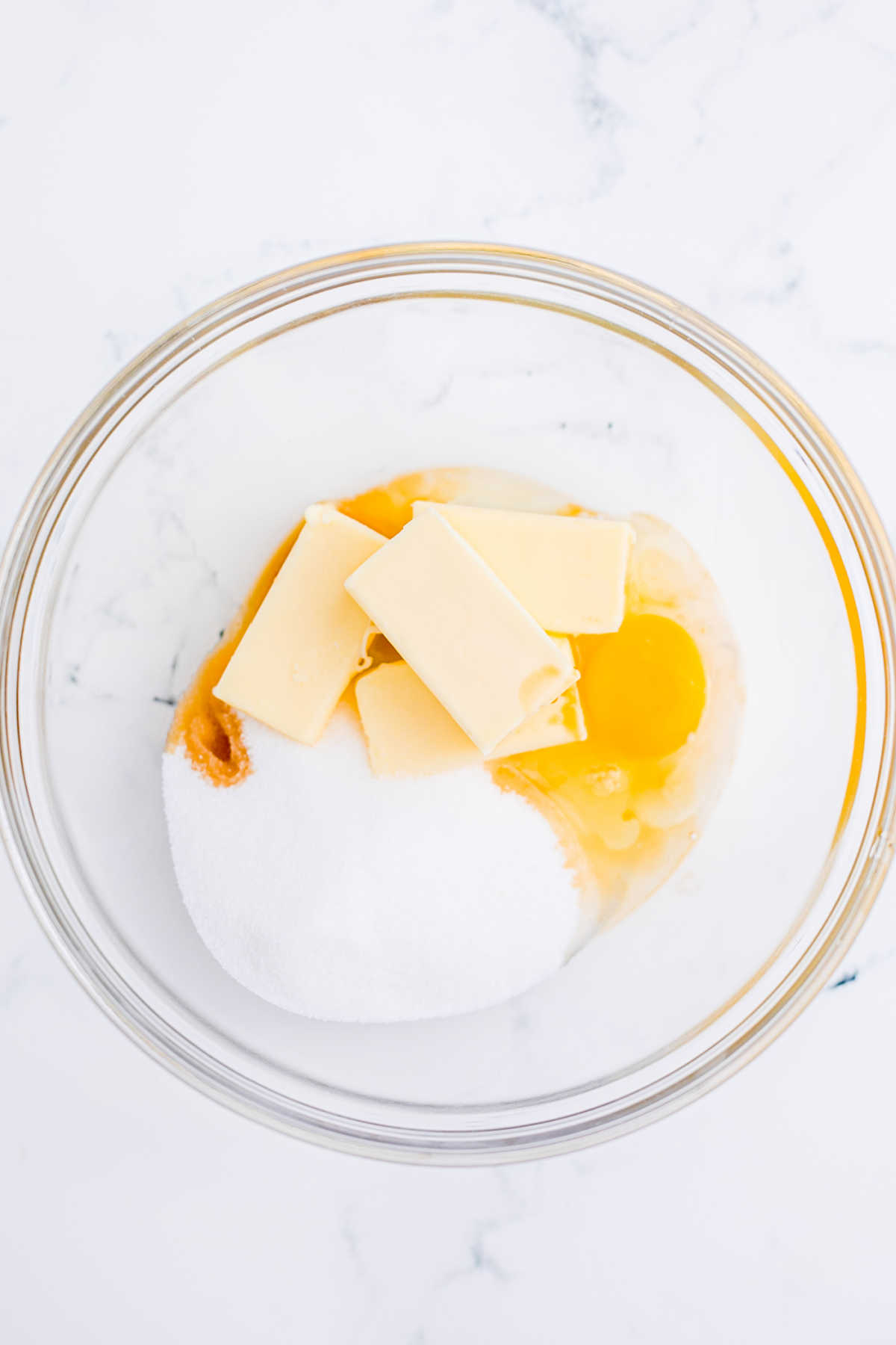 Overhead shot of a mixing bowl with butter, eggs and sugar.