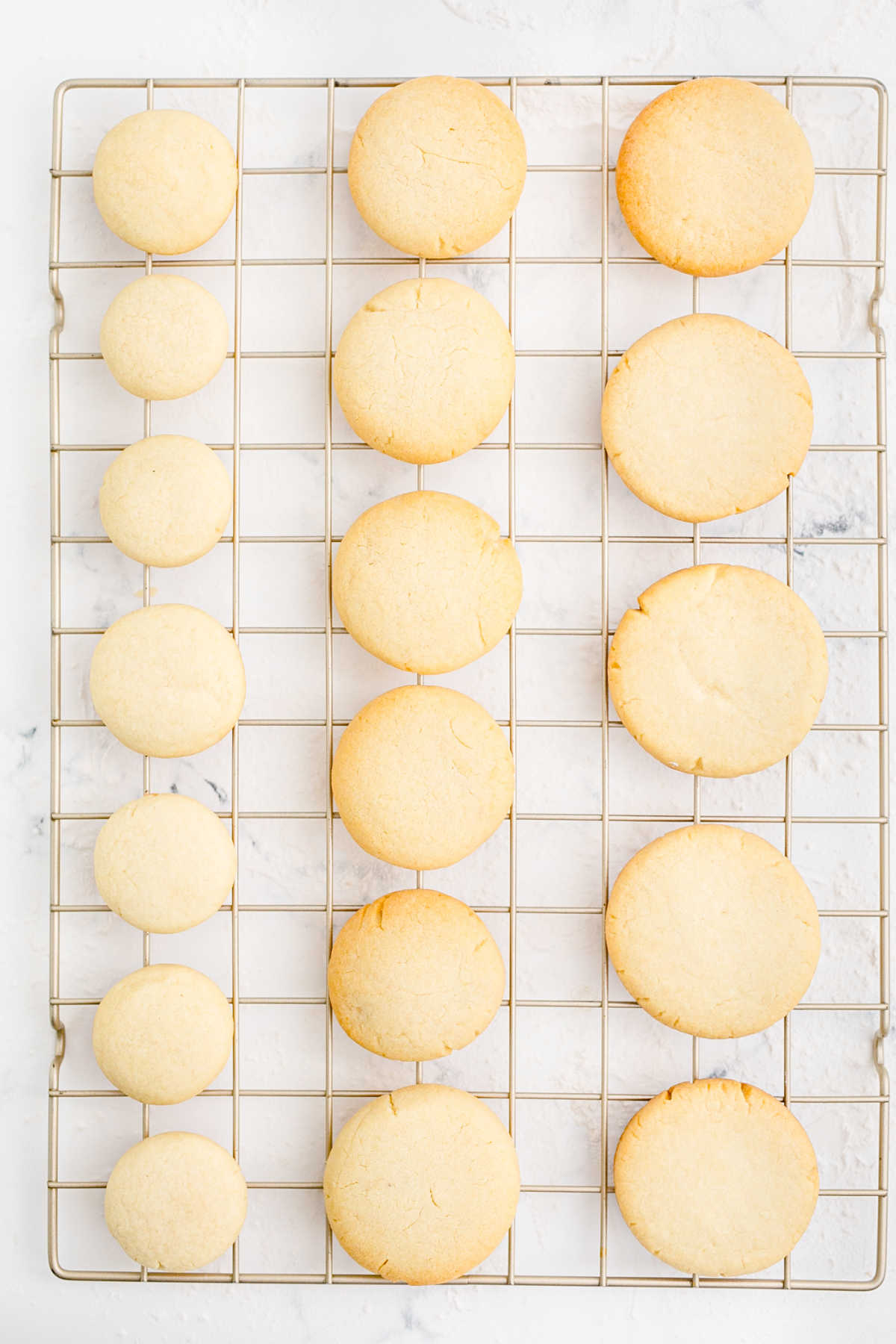 A wire rack with different size cookies.