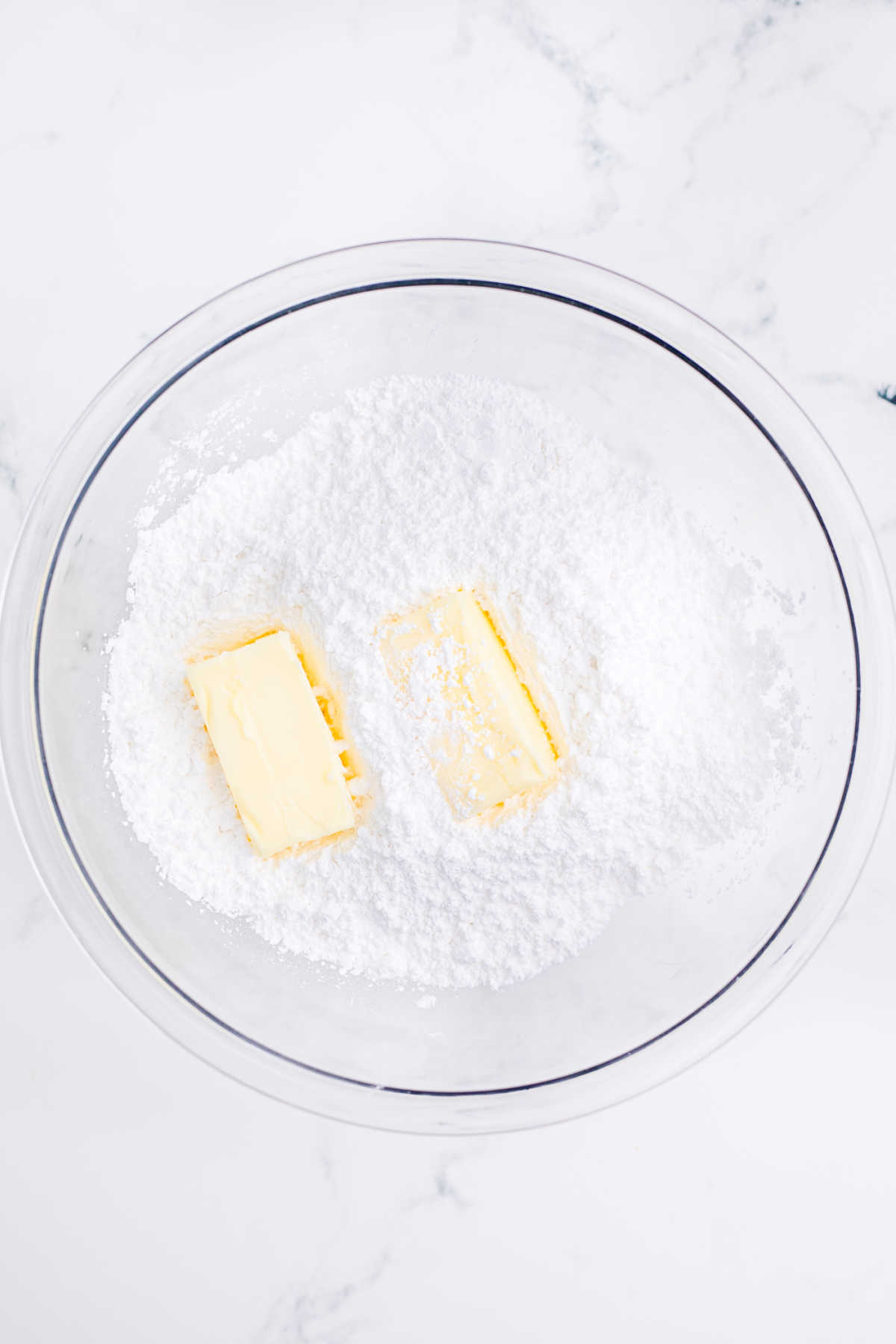 A mixing bowl with butter and powdered sugar.