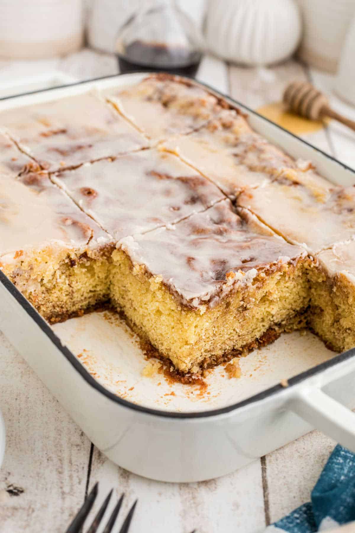 SHot of a baking dish with a honey bun cake with pieces missing.