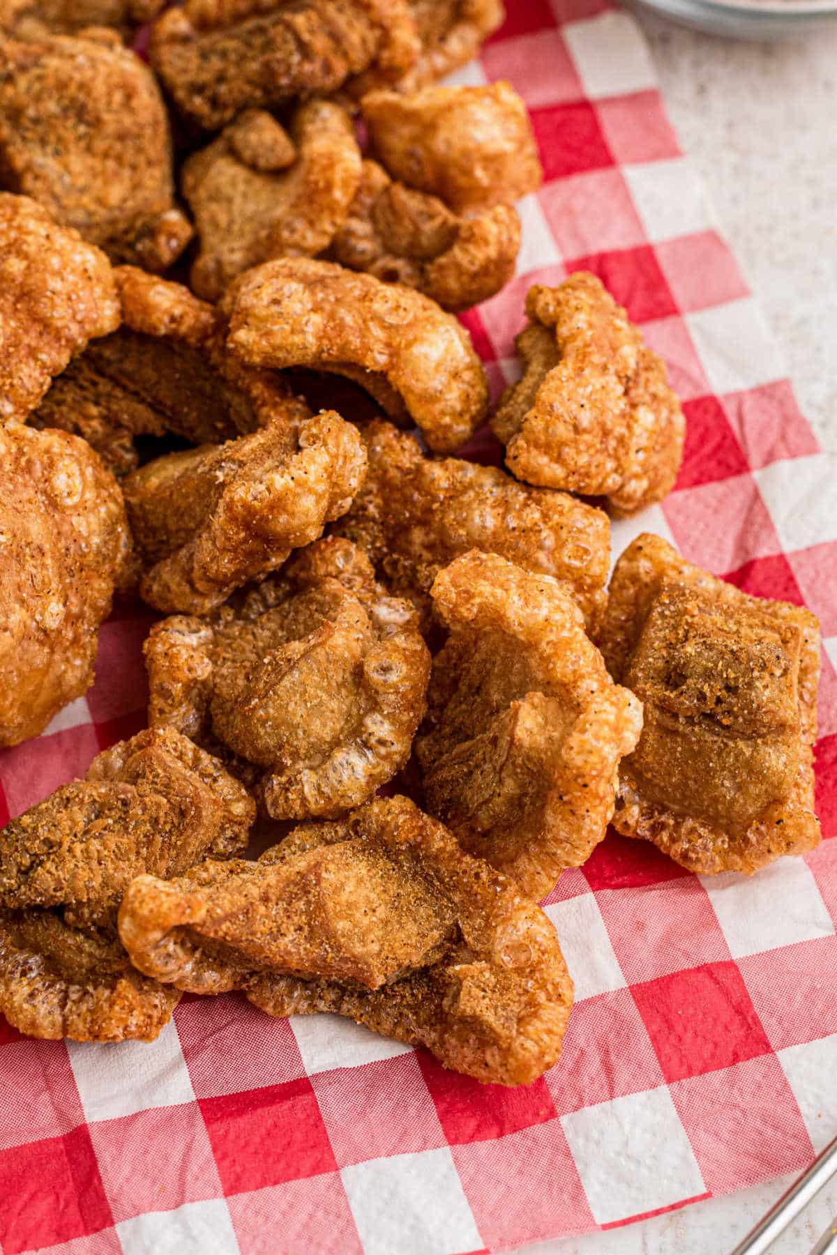 A pile of pork cracklins on a red and white napkin.