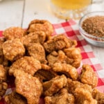 Homemade cracklins on a pile on a red and white checkered napkin.