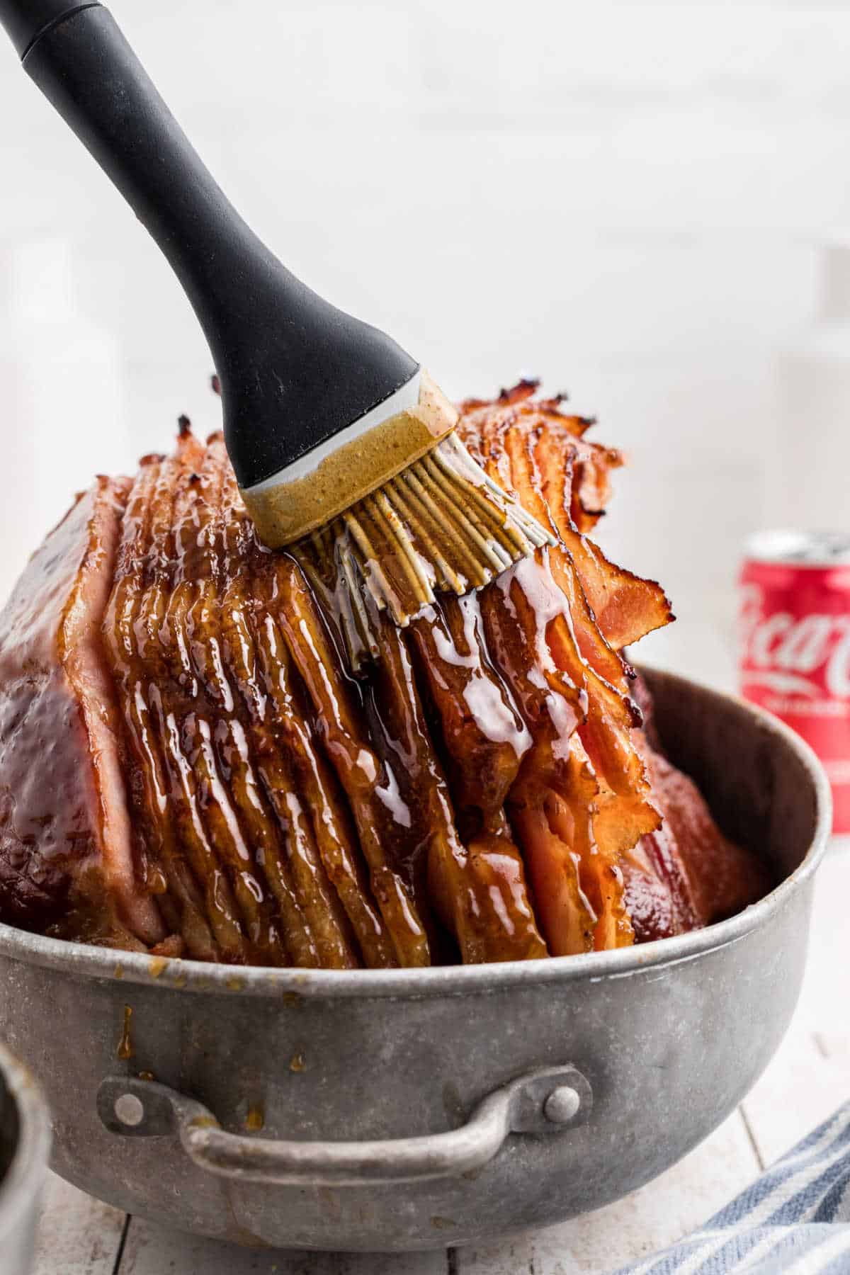 Close up of a basting brush, brushing on a southern coca-cola glaze on a ham.