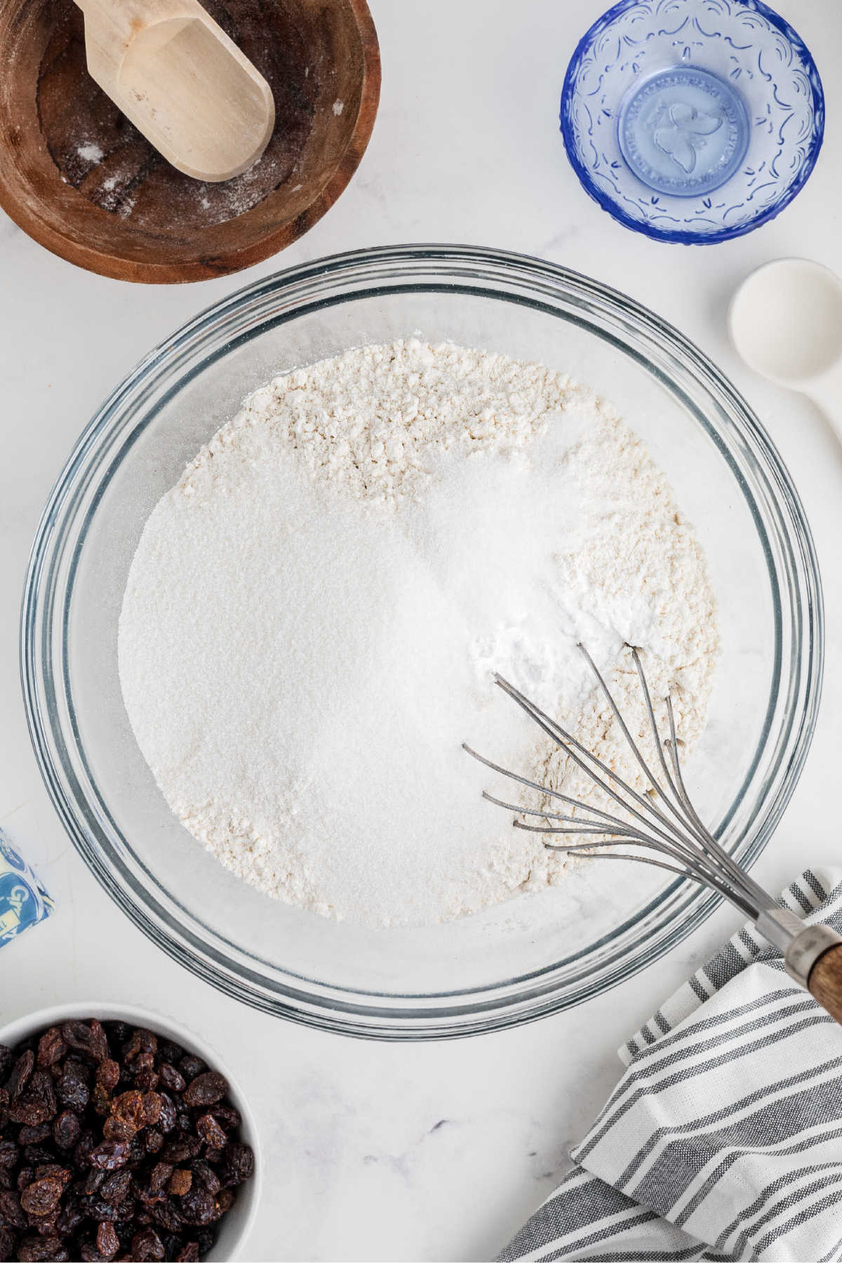 A large bowl with flour and baking soda, with a whisk.