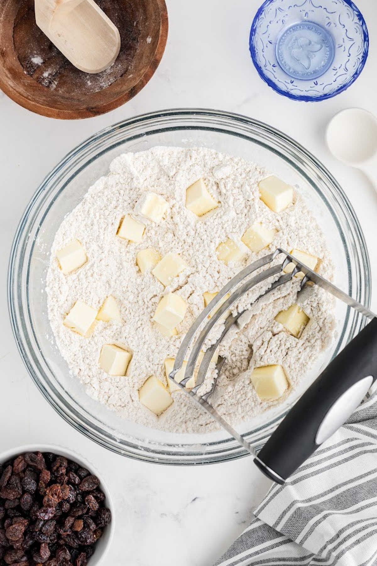 Butter being cut into a bowl of flour, with a pastry cutter.