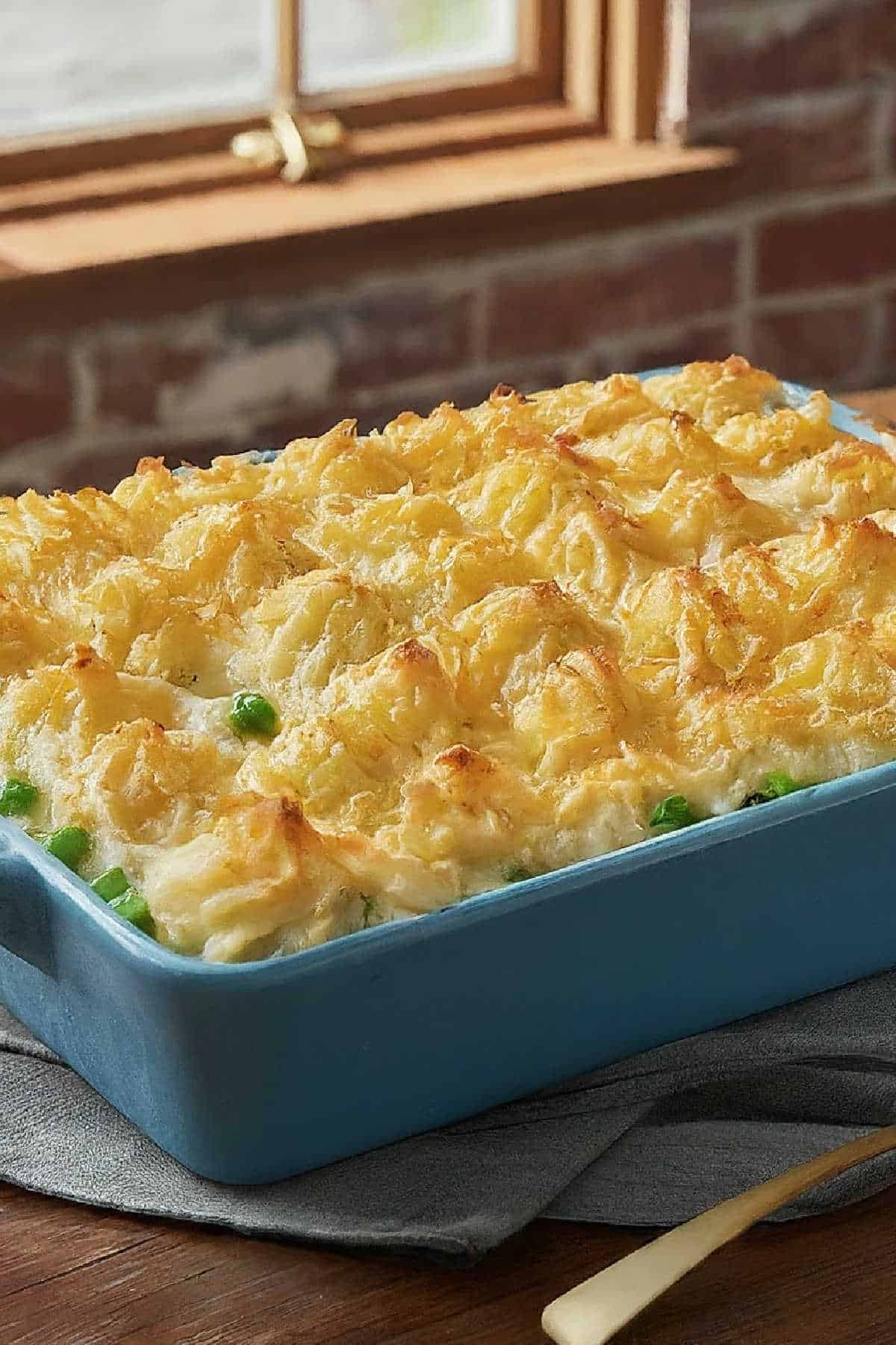 A casserole dish filled with fishermans pie, with piped mashed potatoes on top.