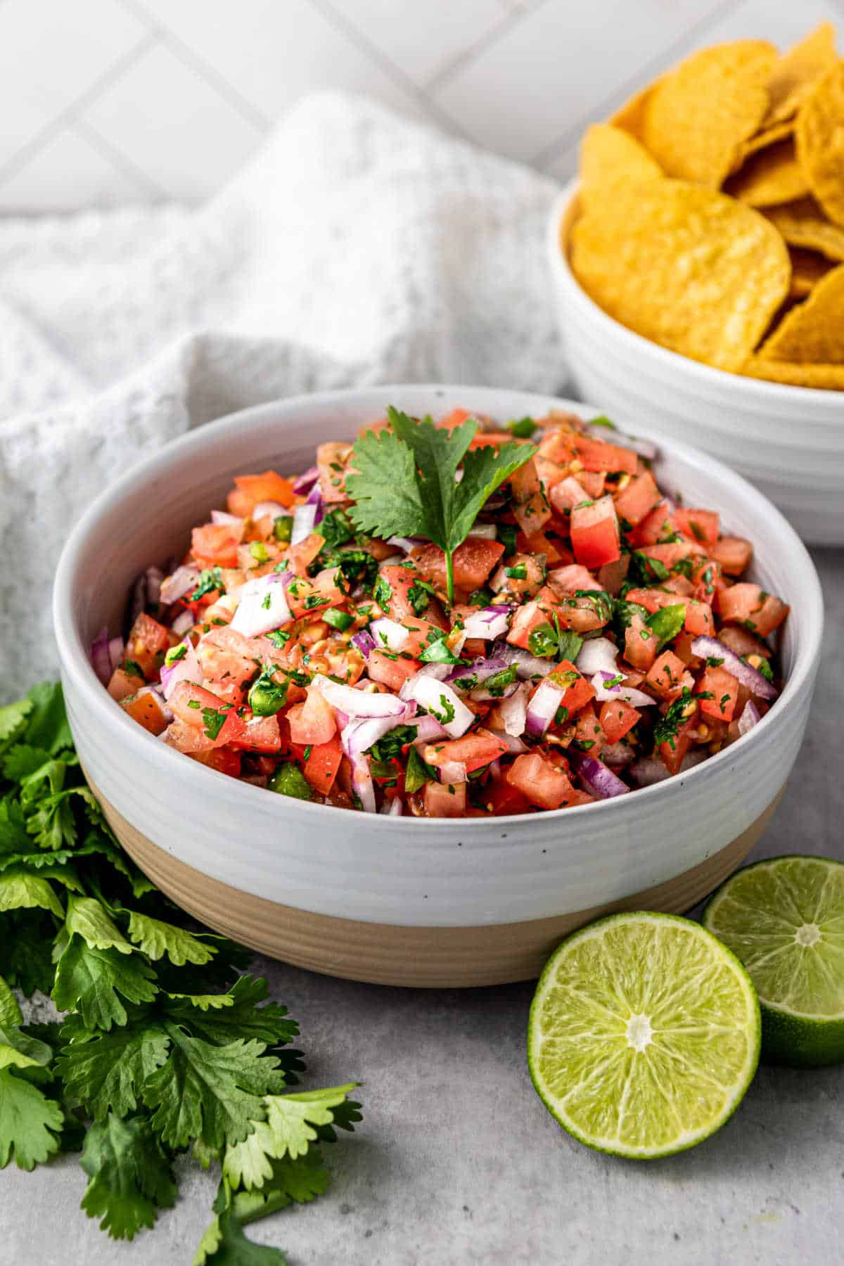 A delicious salsa fresca recipe in a bowl with some chips at the back.