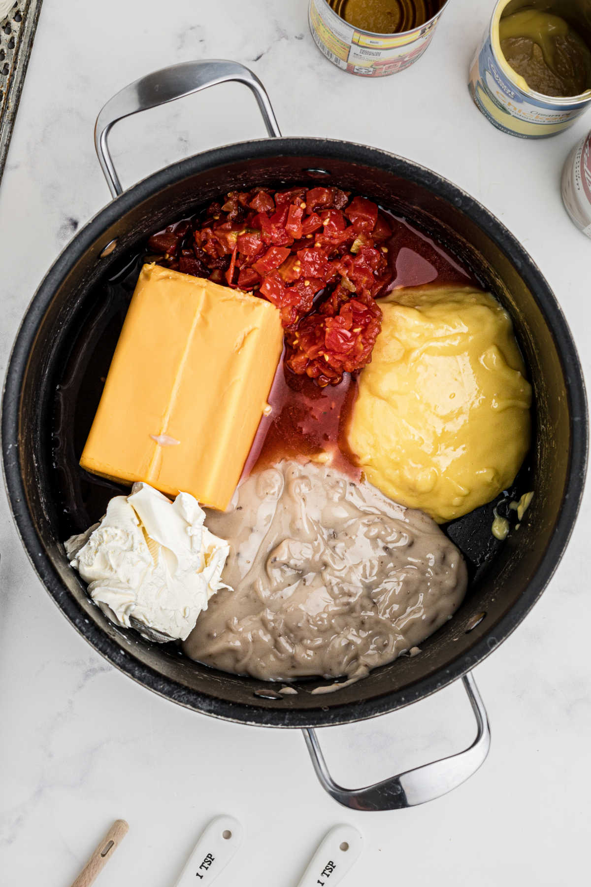 A large pot with tomatoes, cheese, soup and other ingredients about to be cooked together.