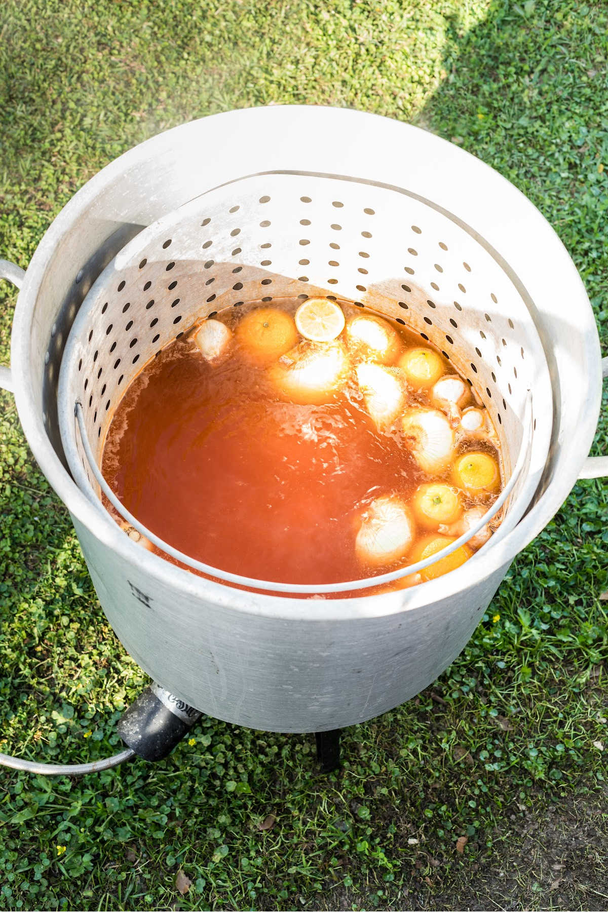 A large seafood boiling pot with seasoned water and vegetables cooking.
