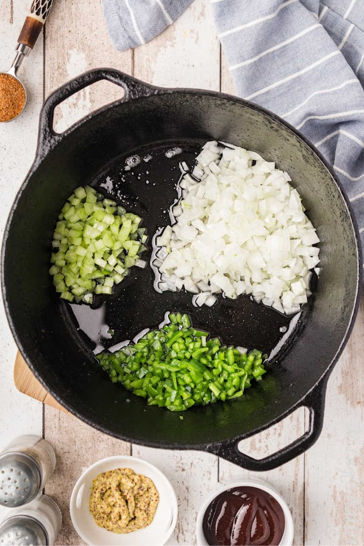 Onions, bell peppers and celery added to a cast iron pot.