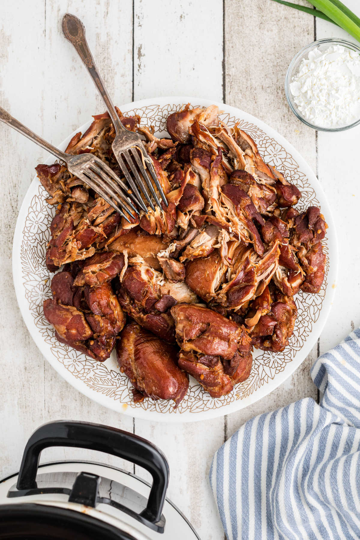 A plate of shredded chicken with two forks.