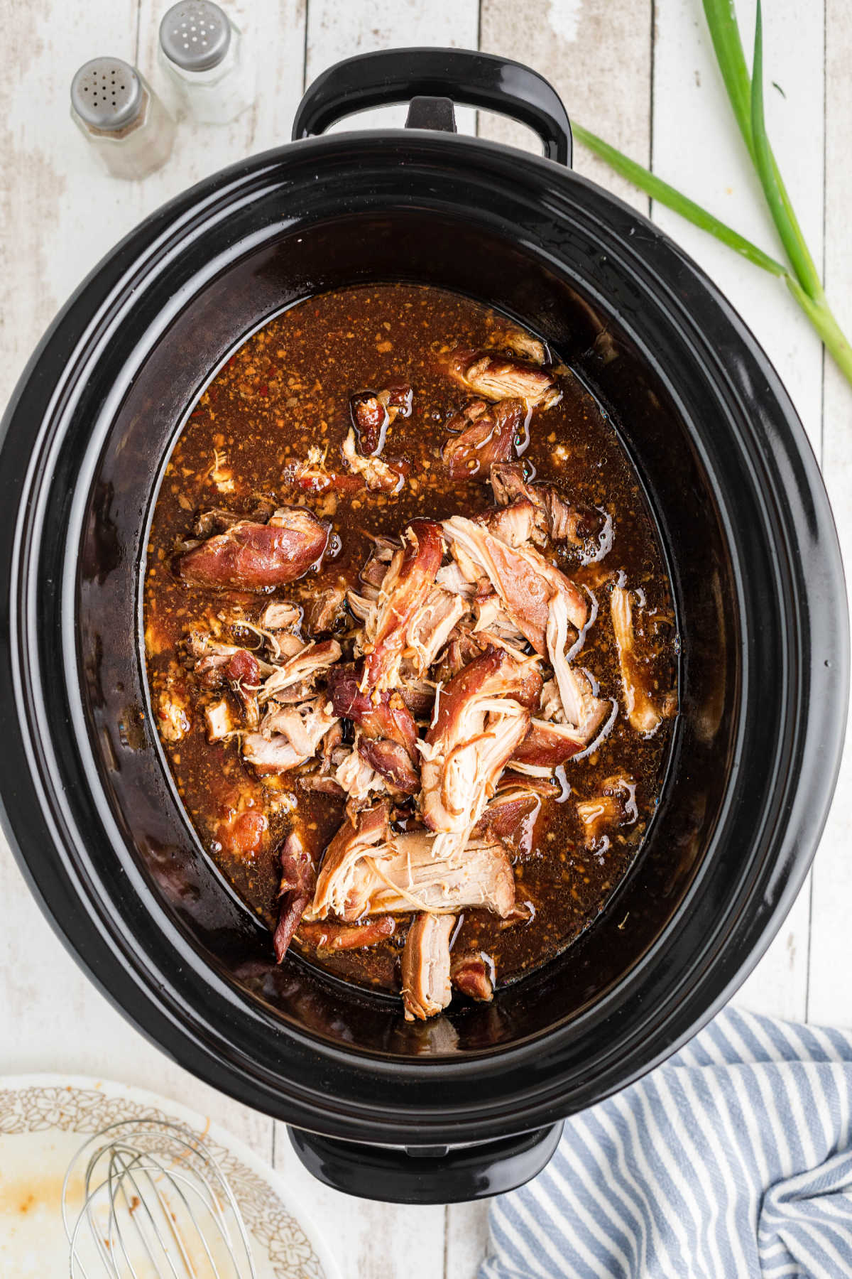 Shredded chicken added to a slow cooker with a bourbon sauce.