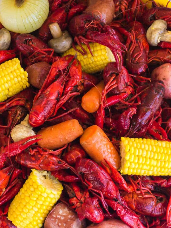 A large platter of boiled crawfish from a crawfish boil, with corn, sausage, potatoes, mushrooms and dip.