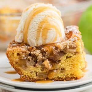 Cropped square image, of a piece of apple pie cake with a scoop of ice cream on top.