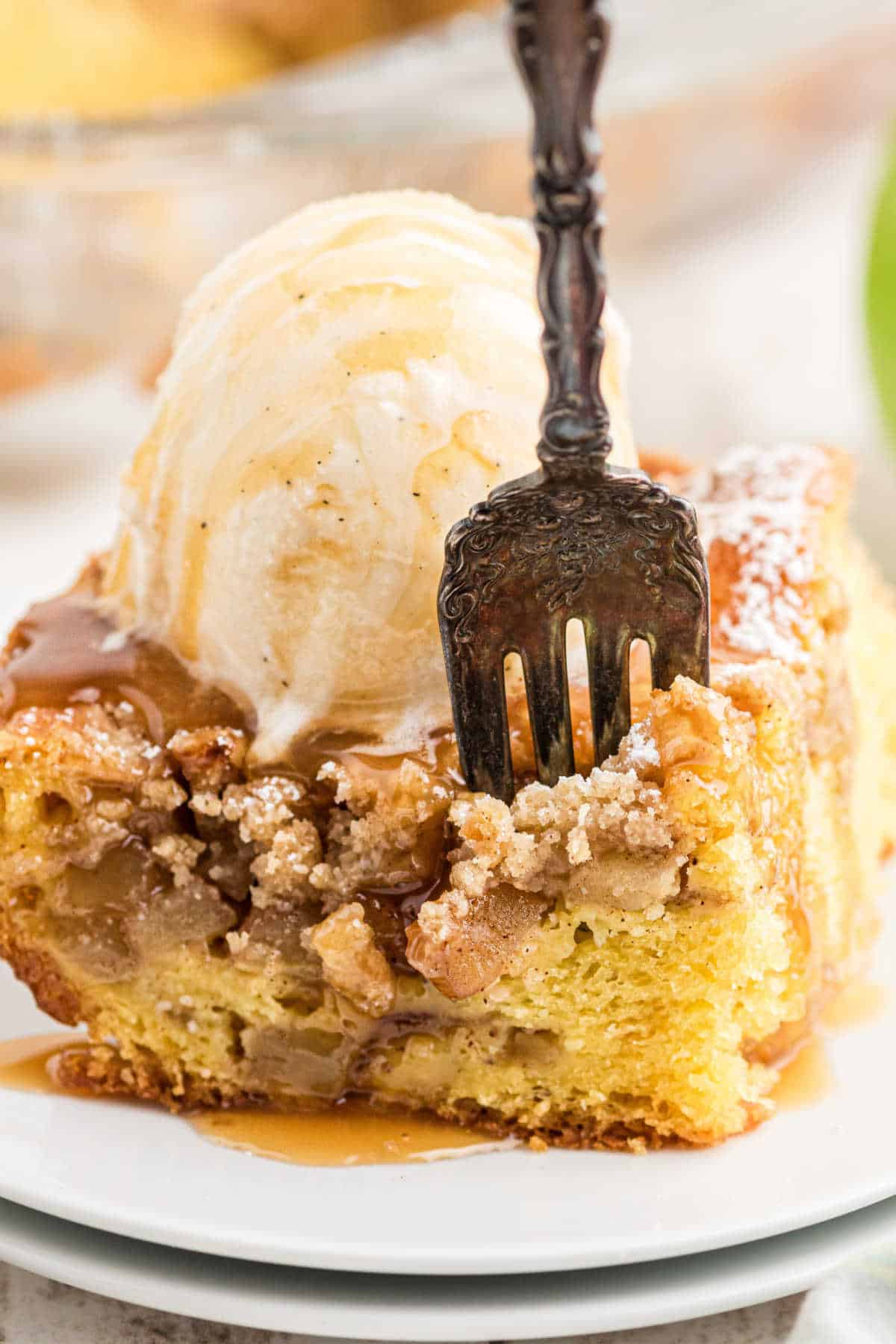 Close up shot of a piece of apple pie cake with a fork digging into it.