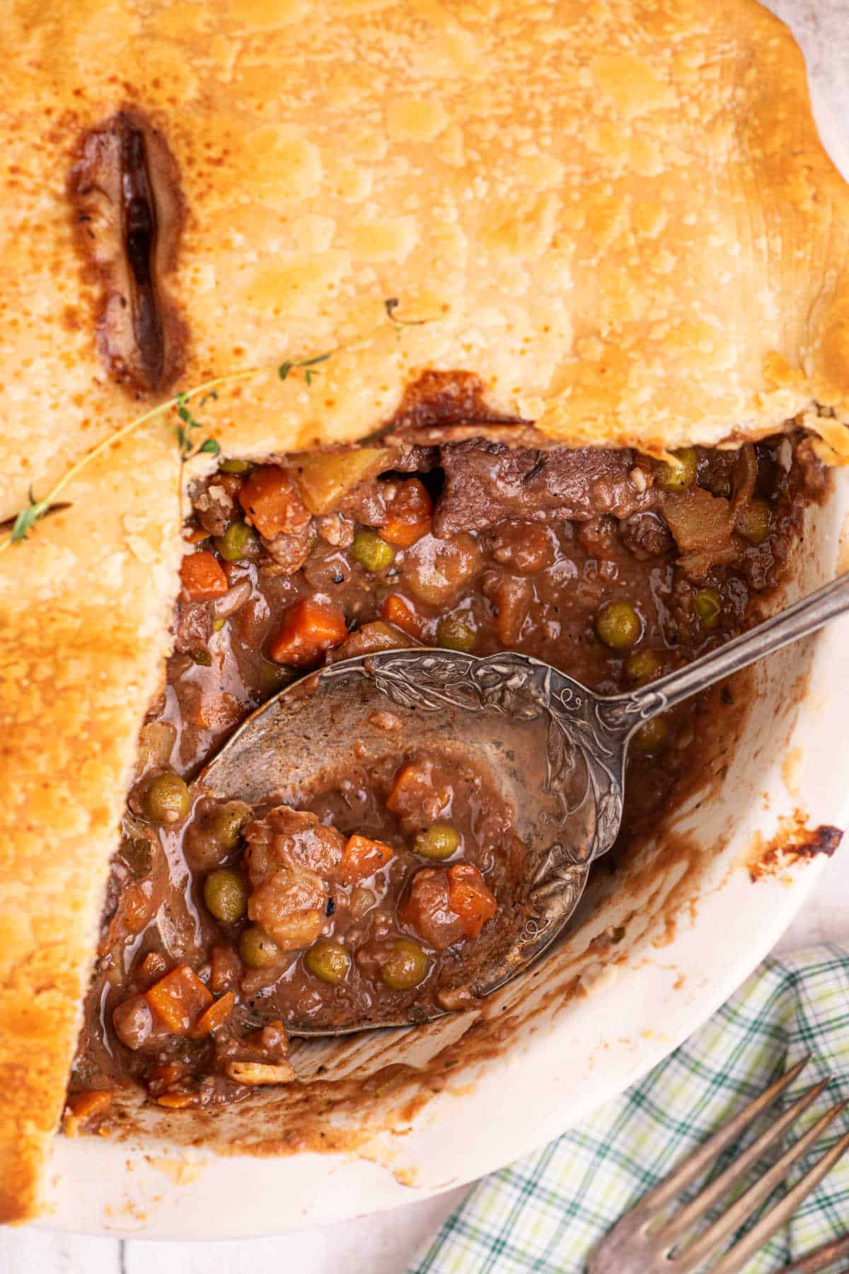 Close up of inside a beef pot pie, with a spoon resting.