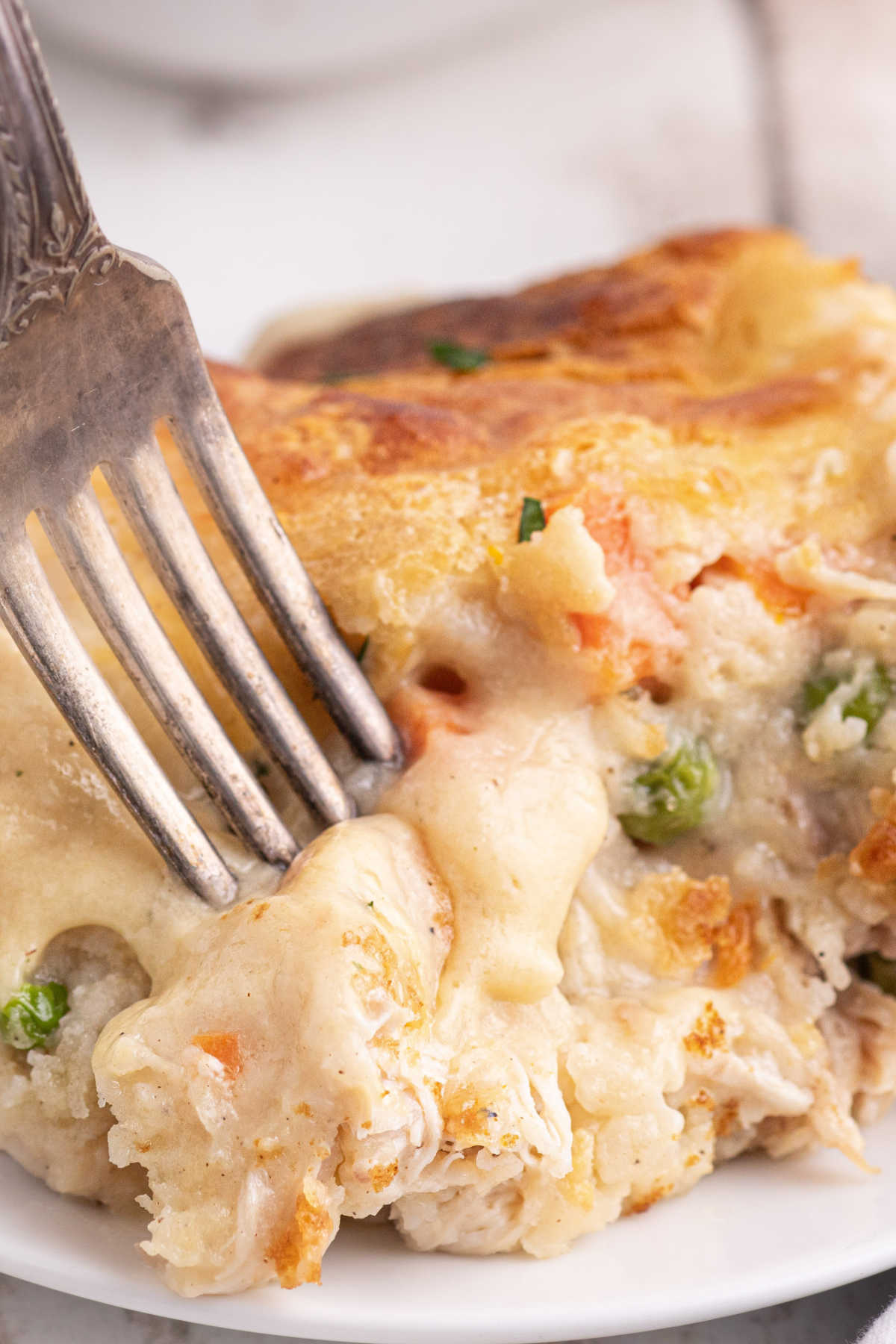 Close up portrait image of a chicken cobbler recipe with a fork digging into it.