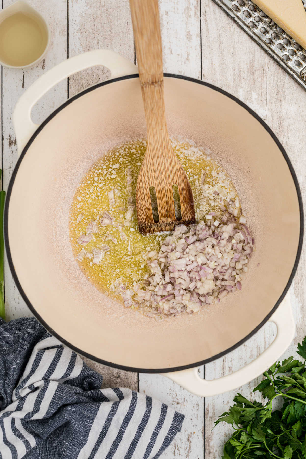 A large Dutch Oven with butter and chopped shallots.