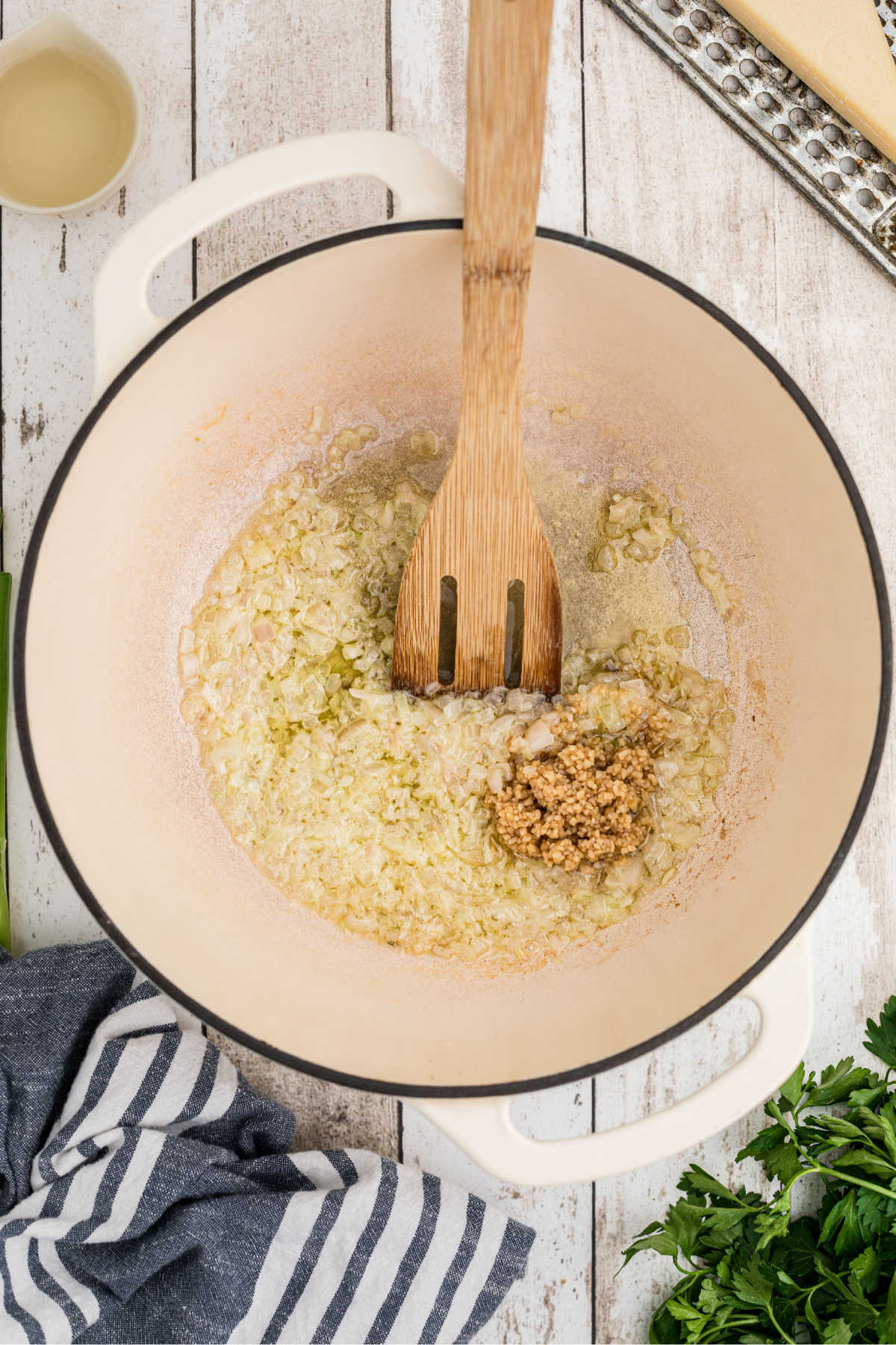 Garlic being added to a large pot with shallots and butter.