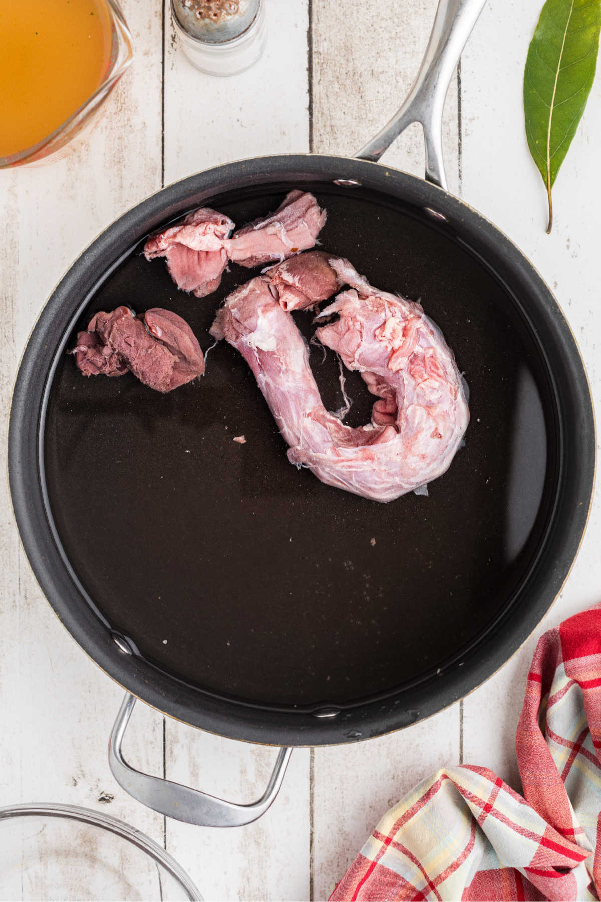 A pot of water cooking some turkey giblets and a turkey neck.
