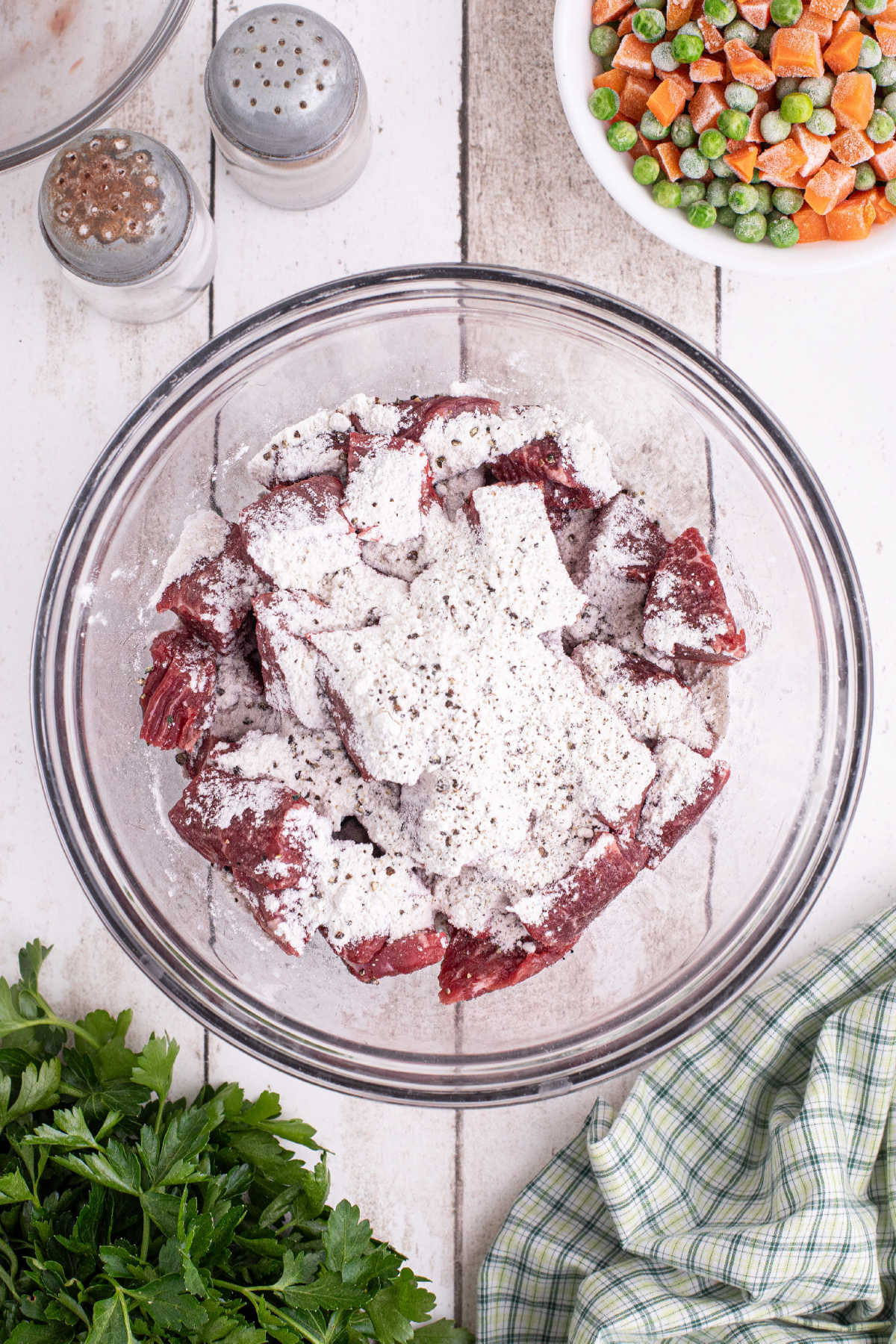 A large mixing bowl with cubed beef, flour and seasoning.