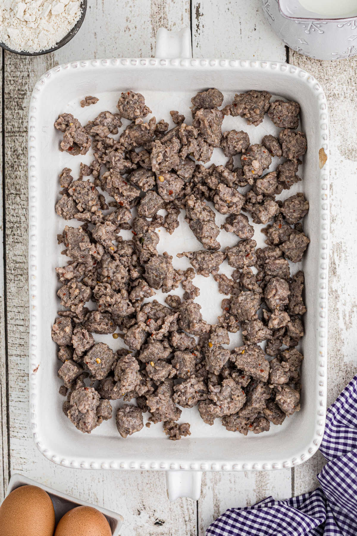 A casserole dish with some browned ground sausage meat in it.