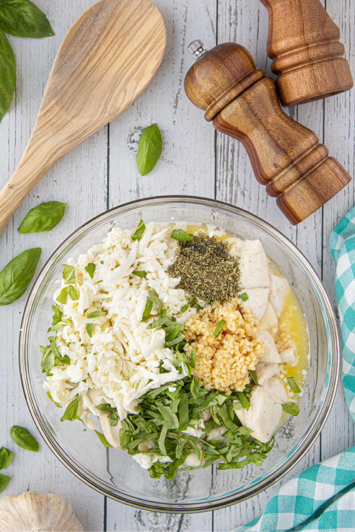 A large mixing bowl with cut refrigerated biscuits, grated cheese and seasonings.
