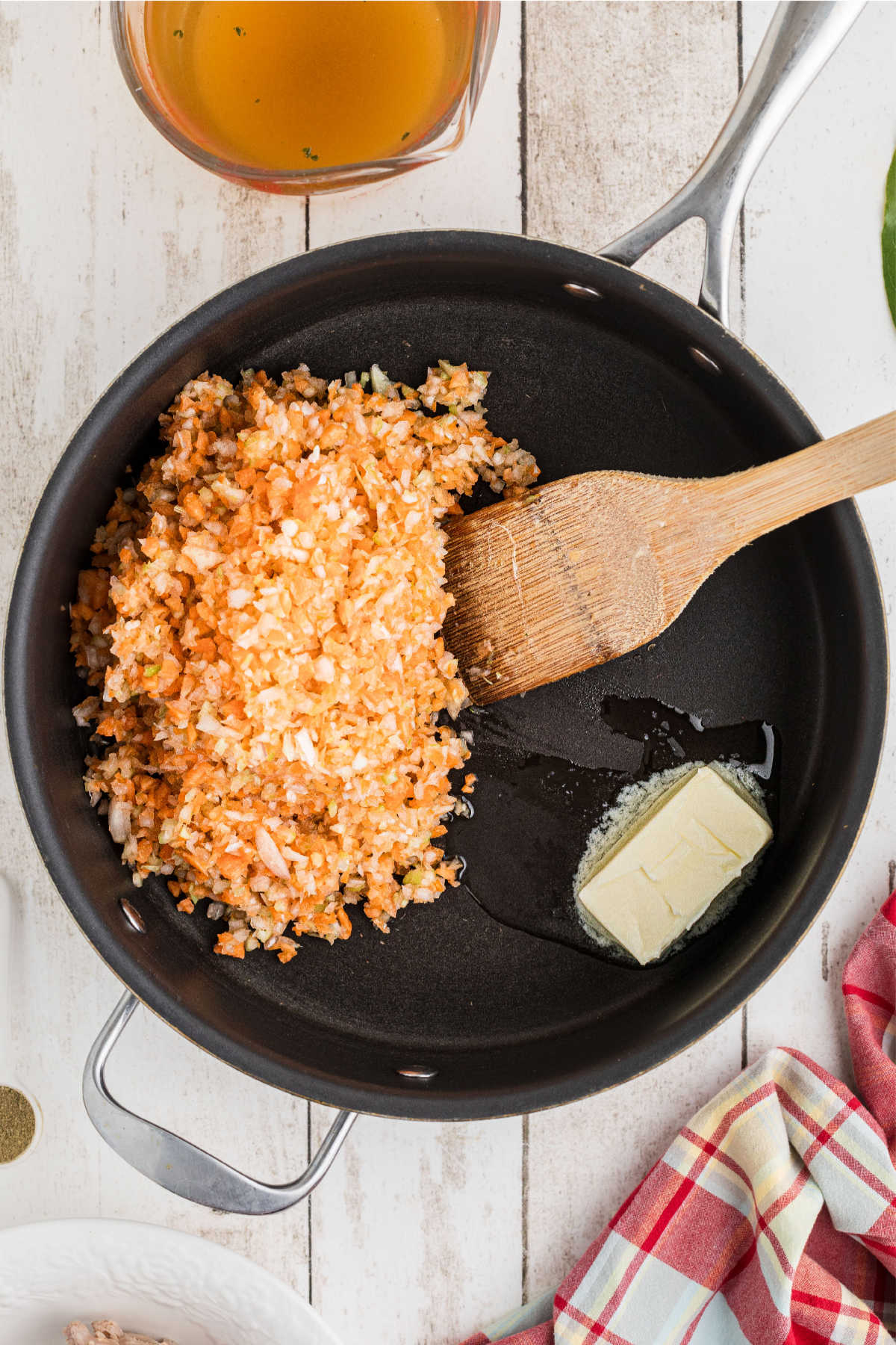 A large skillet with finely diced vegetables and butter.