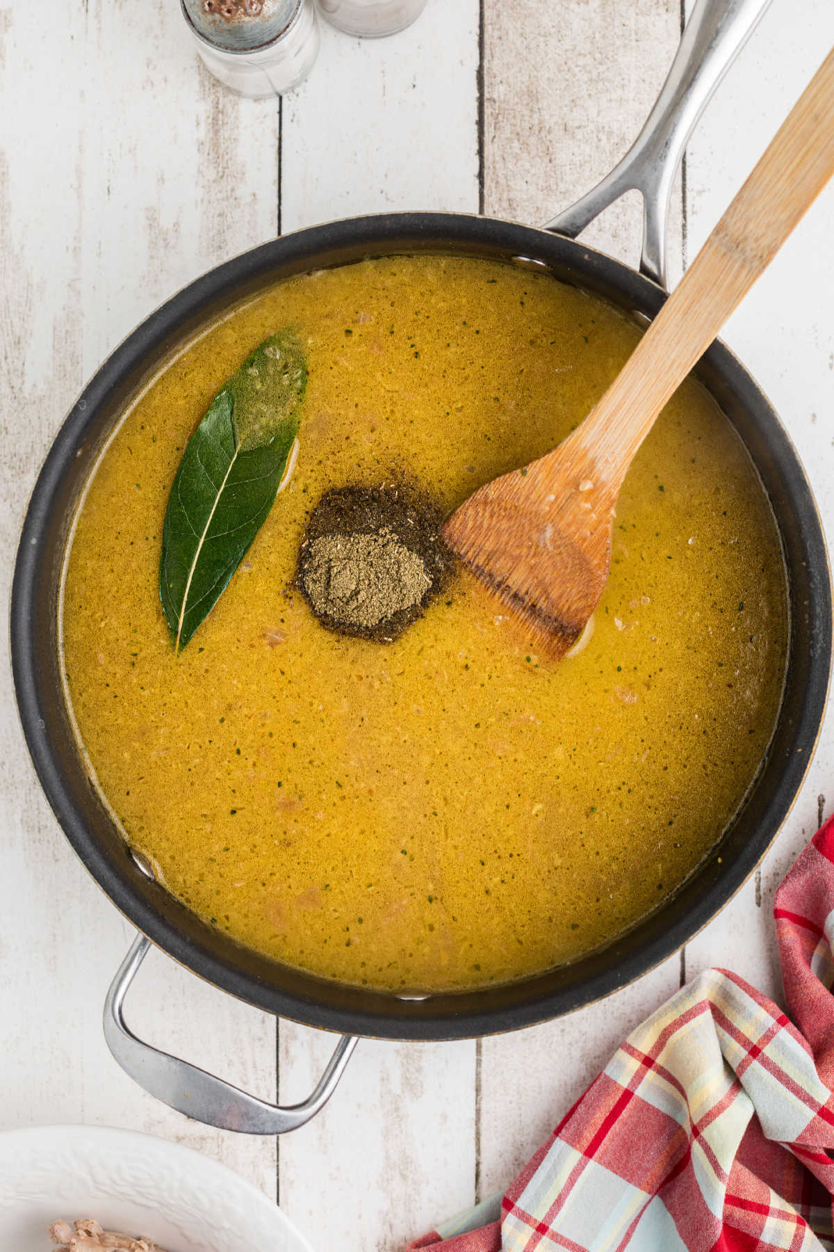 Seasonings added to a skillet of gravy with a bay leaf.