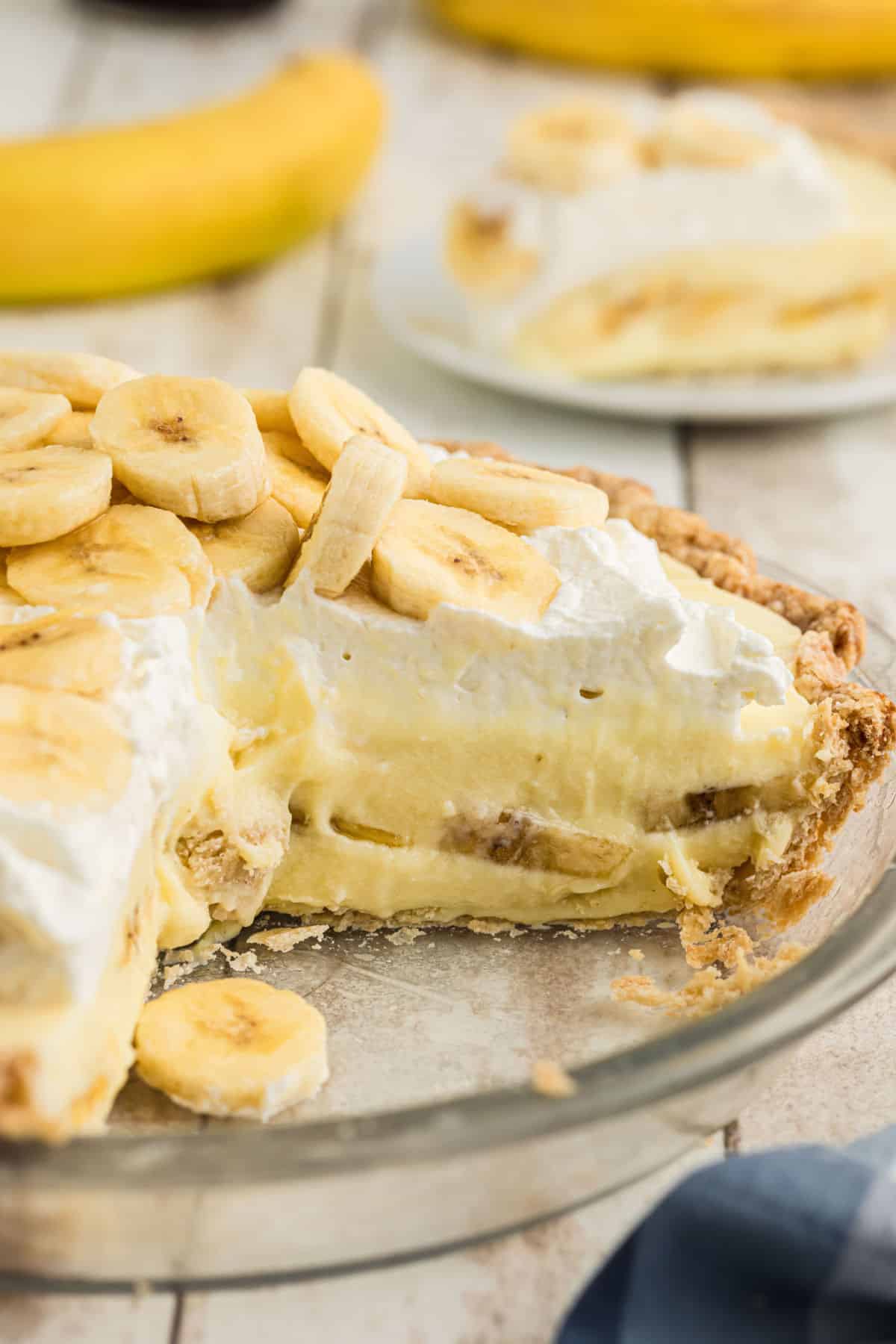 A dish full of banana cream pie with some slices missing.