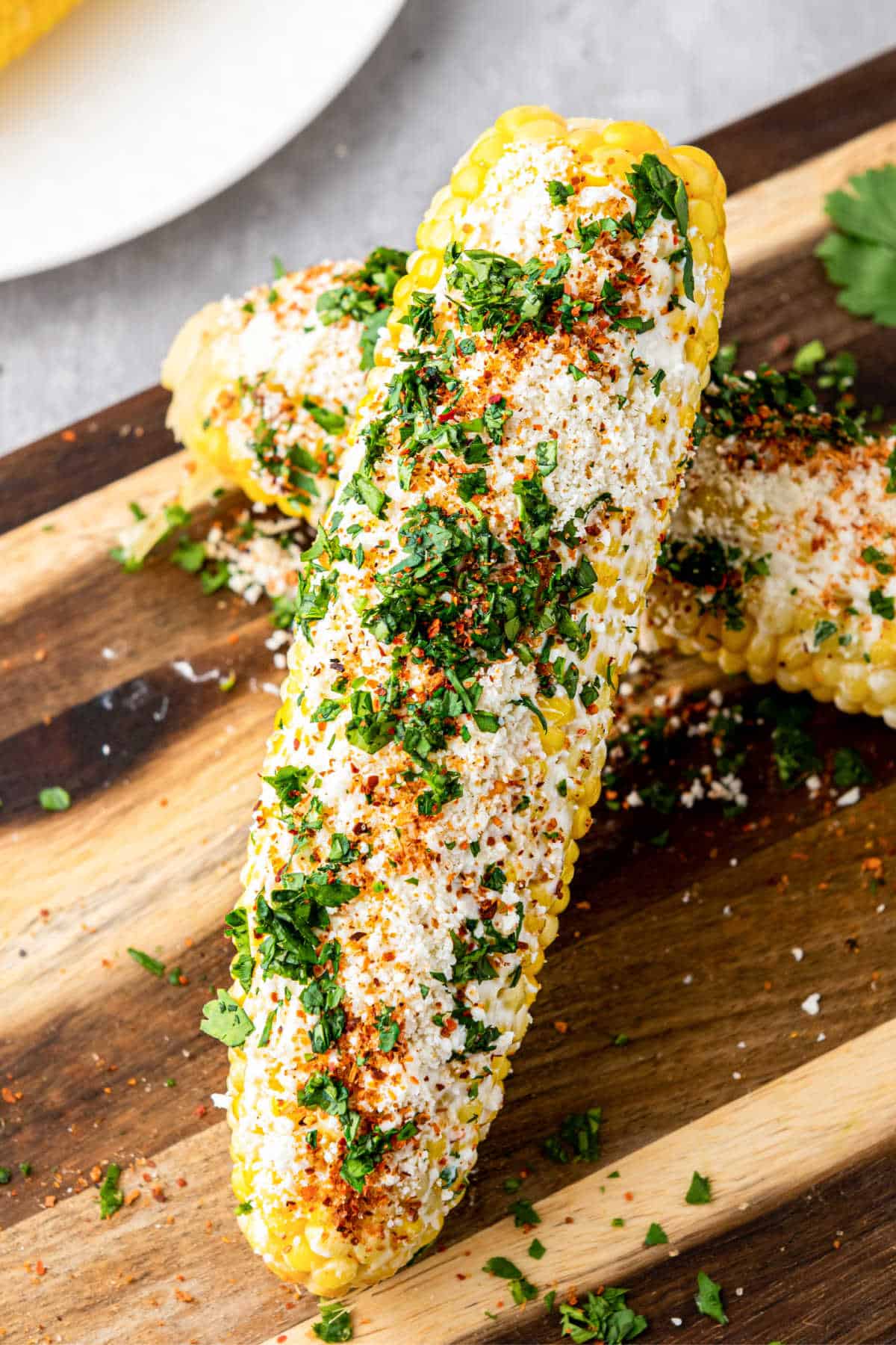 Two ears of corn, dressed as Mexican Street Corn, with one resting on the other.