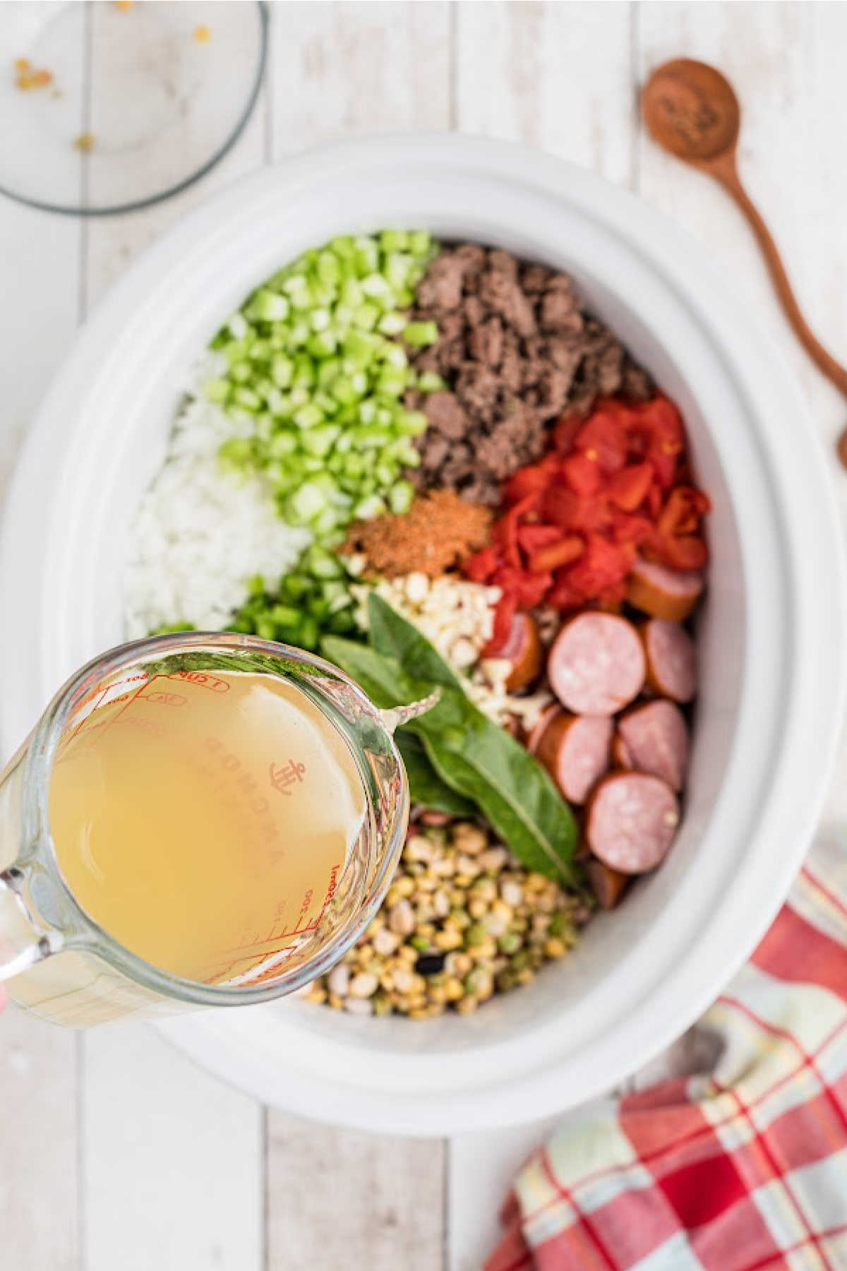 Chicken broth being poured into a slow cooker.