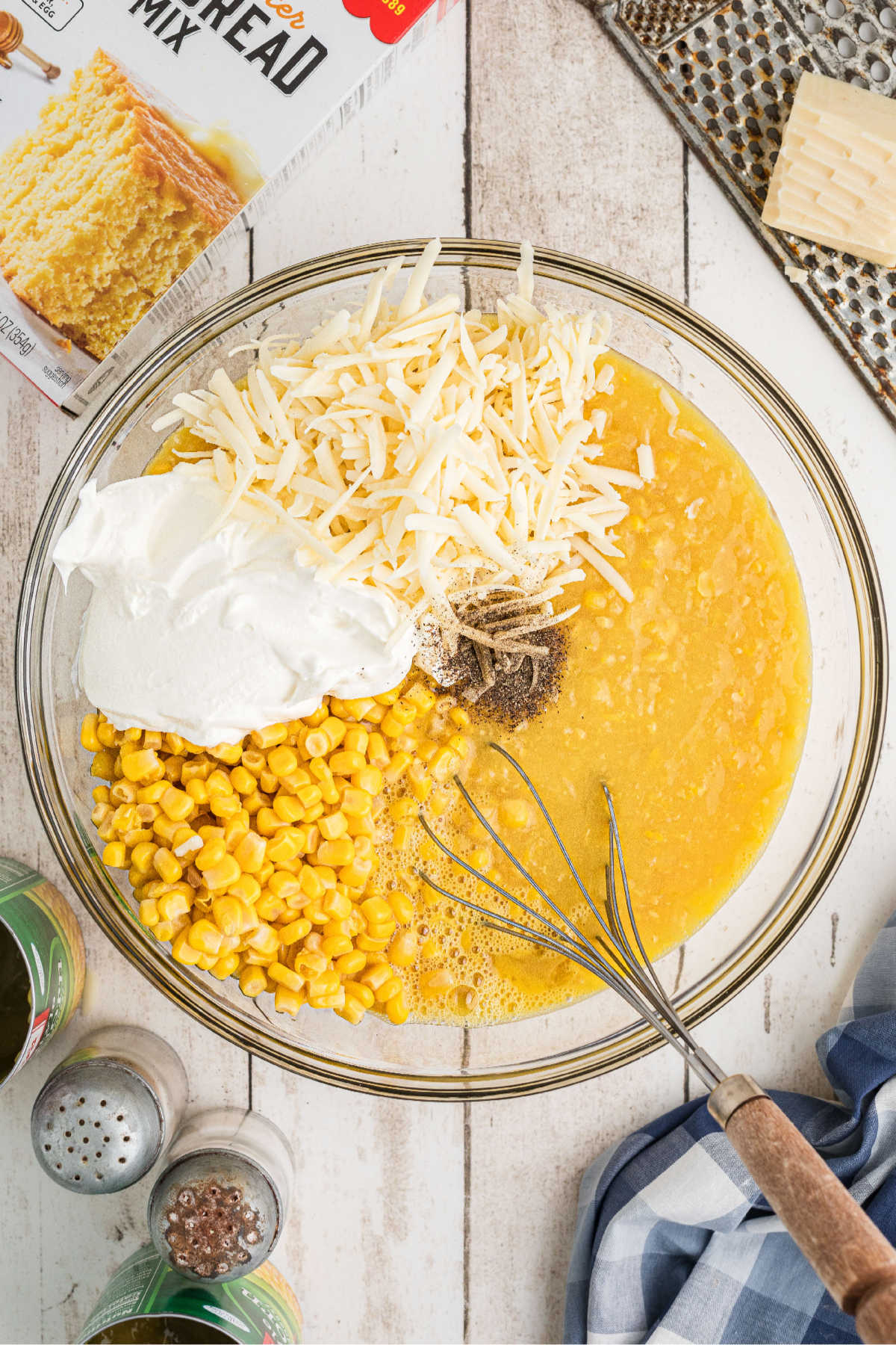 A mixing bowl filled with corn, cream style corn, sour cream and cheese.
