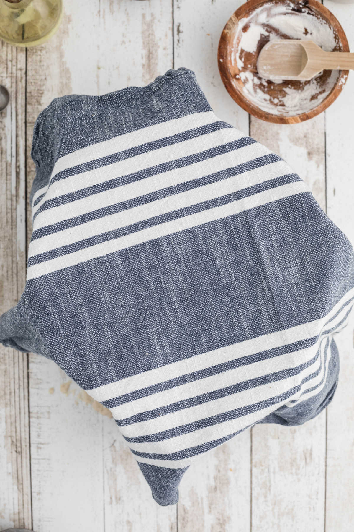 A mixer bowl that has been covered with a kitchen towel.