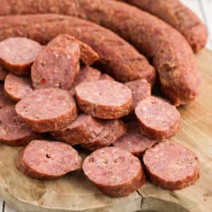 Andouille sausage sliced on a board, image is cropped square.