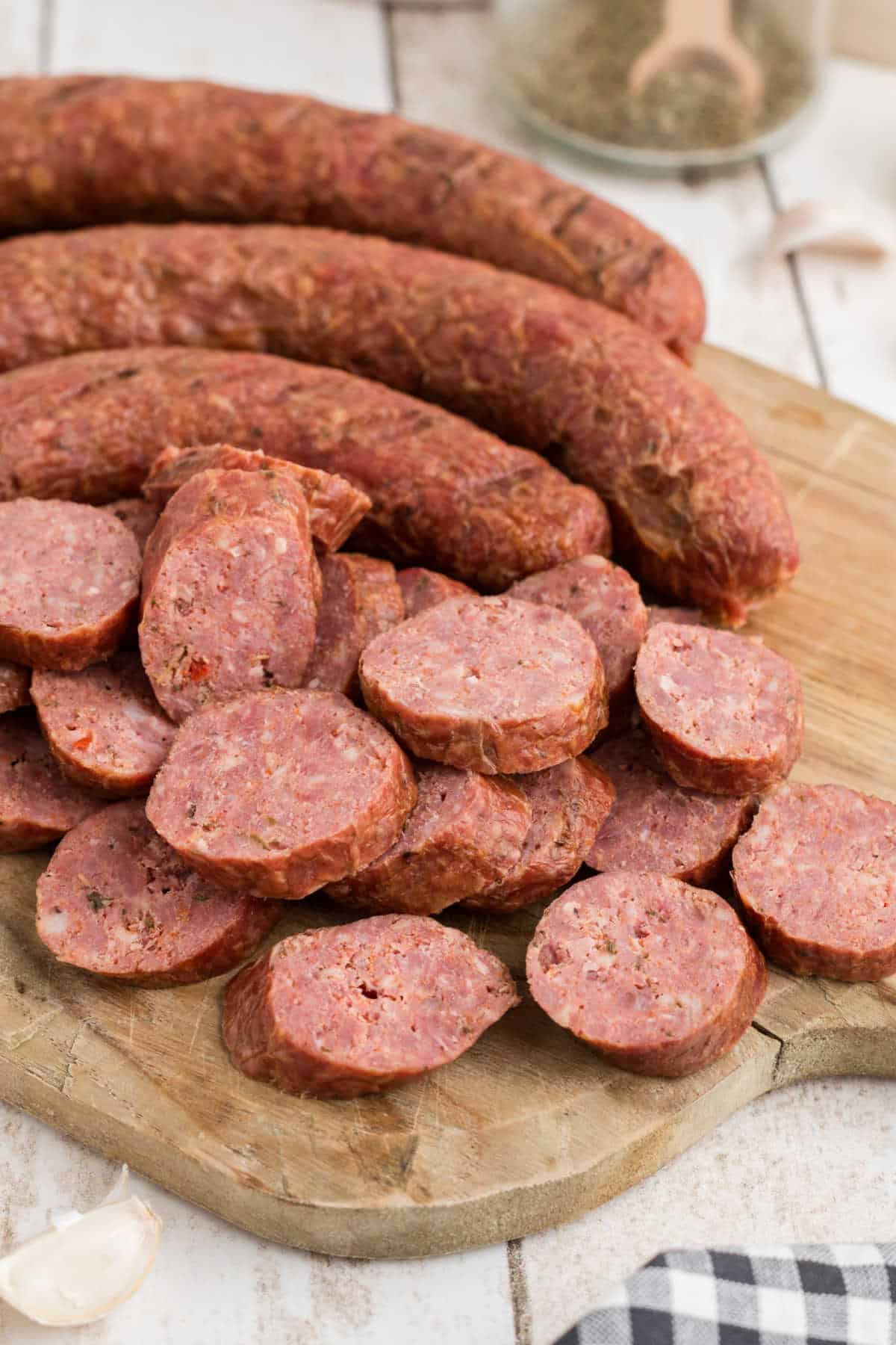 A chopping board with some andouille sausage sliced into coins.