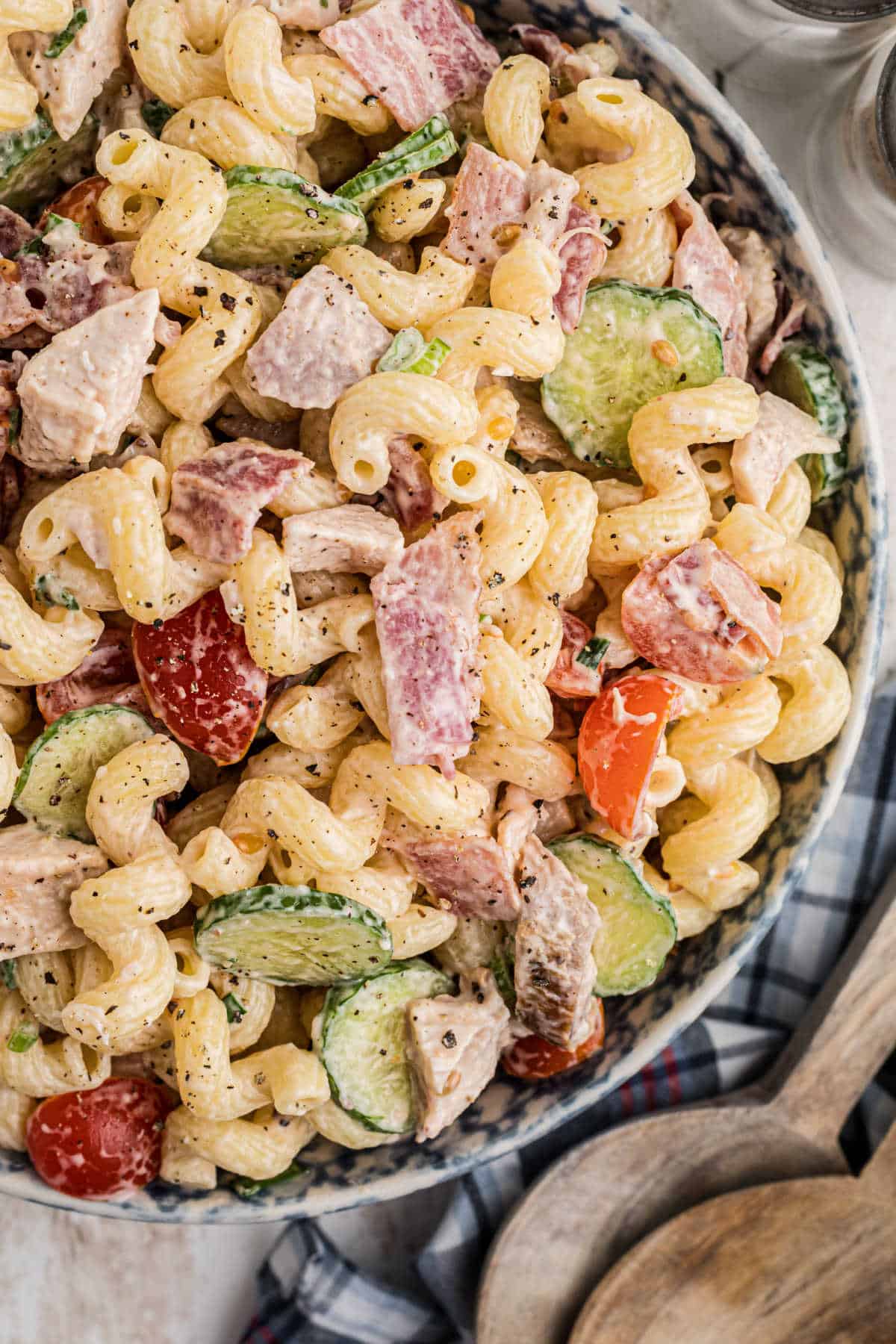 Overhead close up shot of a bowl of pasta salad, with curly noodles and chicken and bacon.